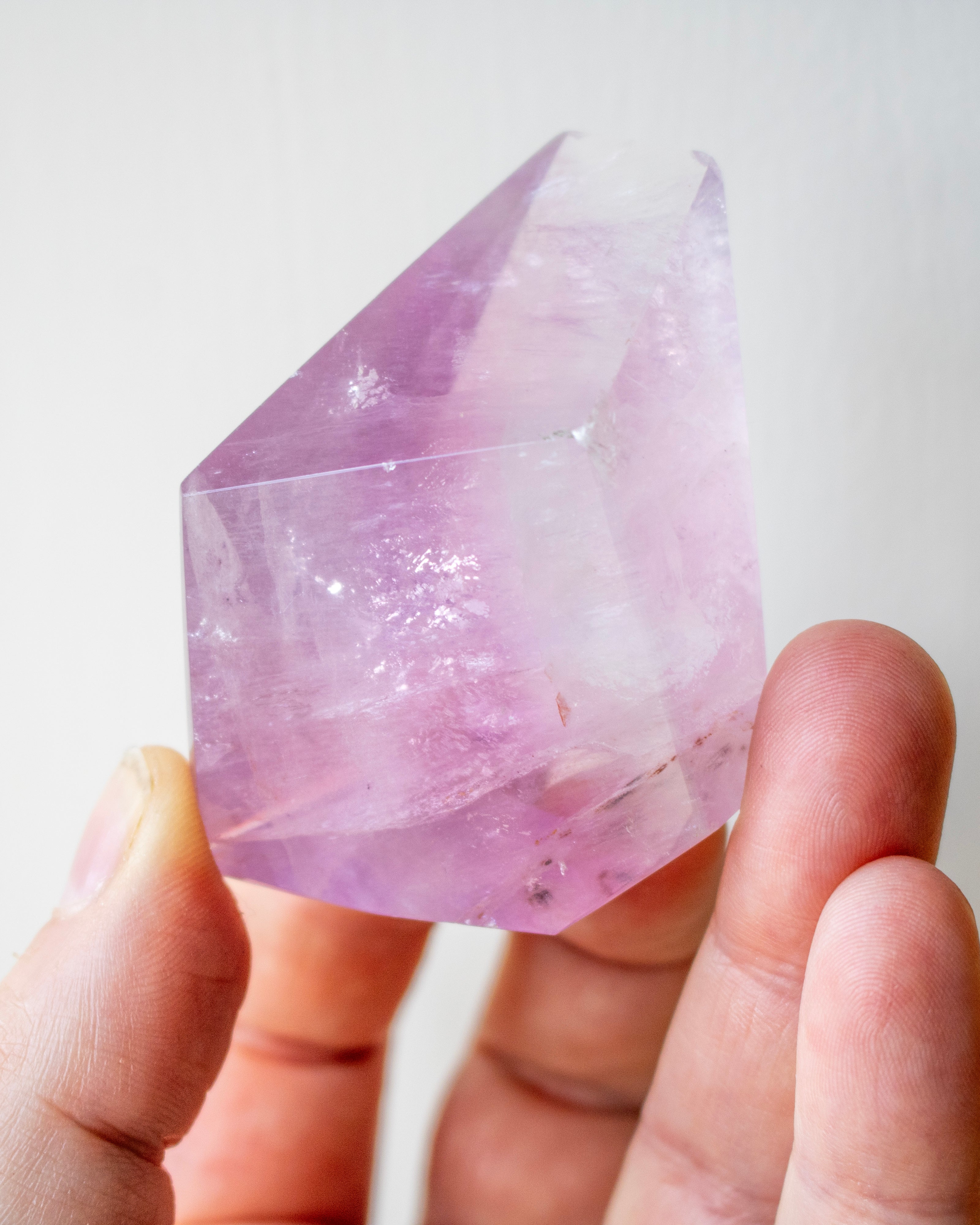 Hand holding a pink crystal against a white background