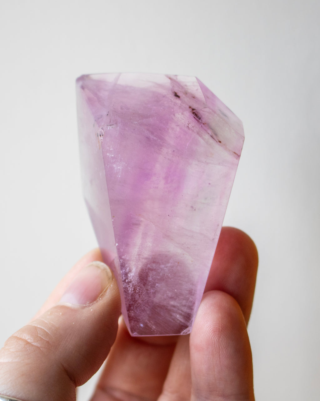 Hand holding a pink crystal against a white background