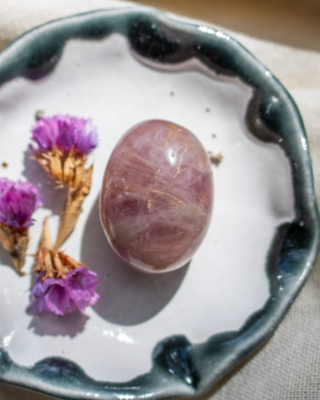 Purple stone on a ceramic dish with purple flowers