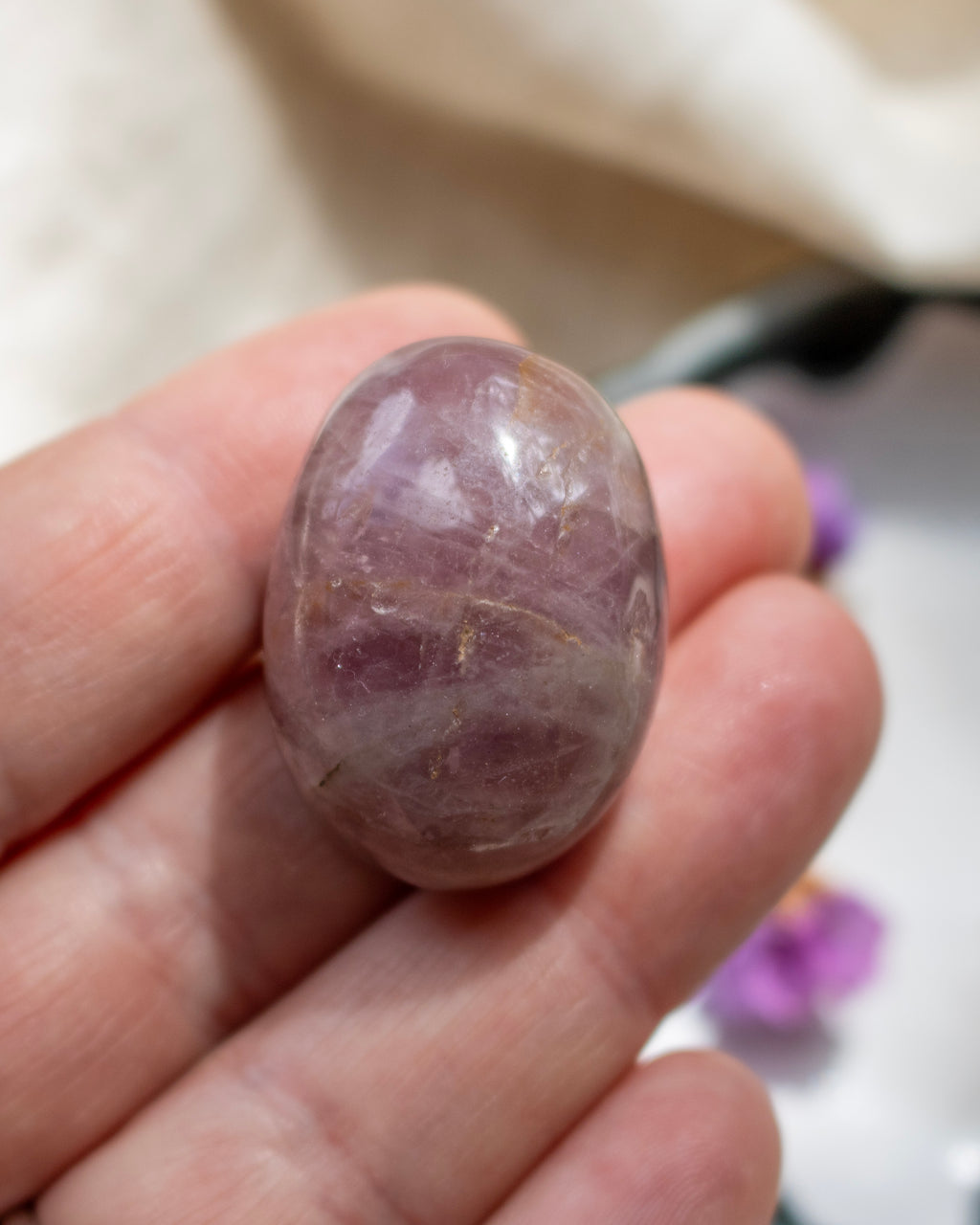 Purple stone held in a hand with a blurred background