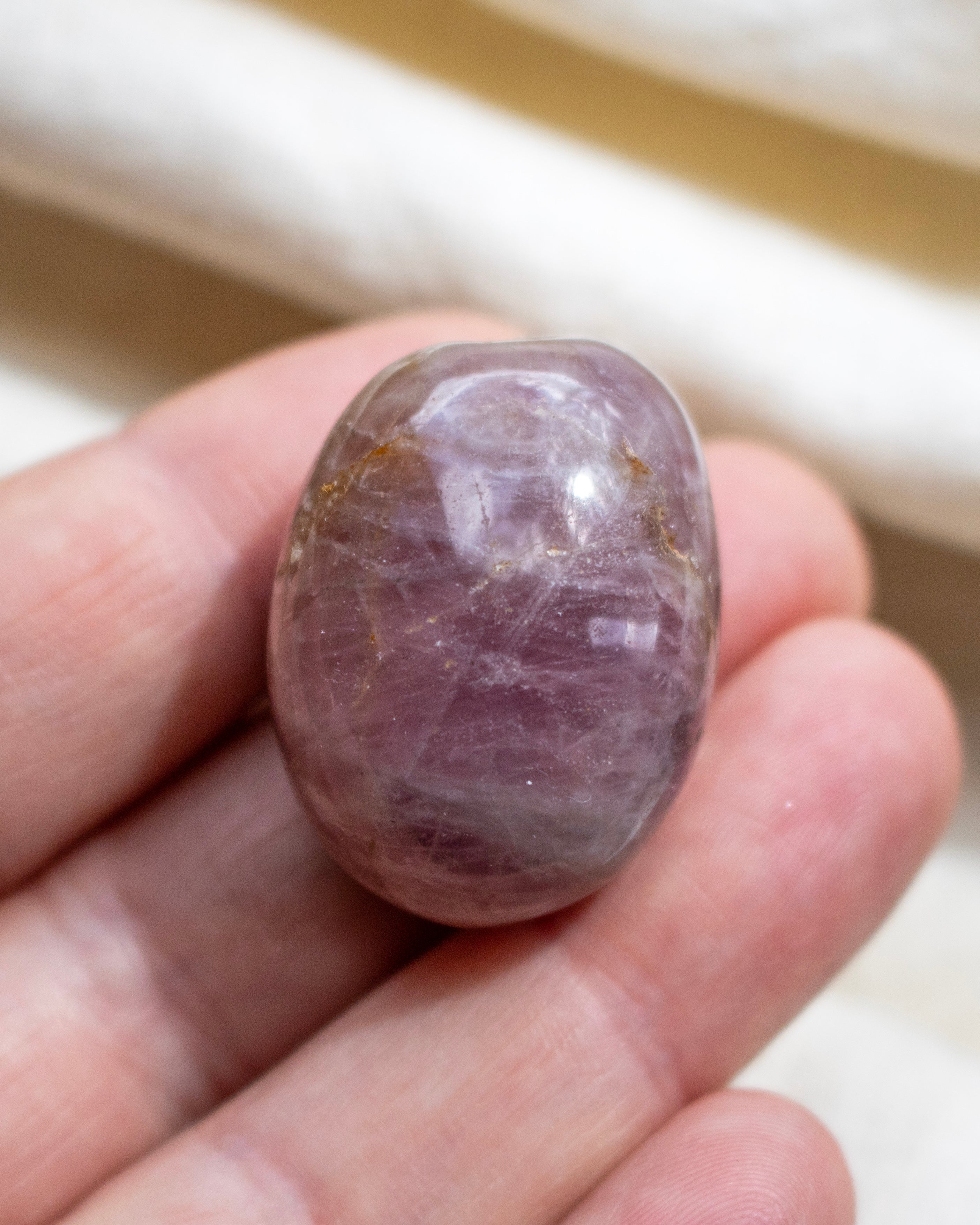 Purple crystal held in a hand with a neutral background