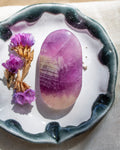 Purple crystal on a white dish with purple flowers