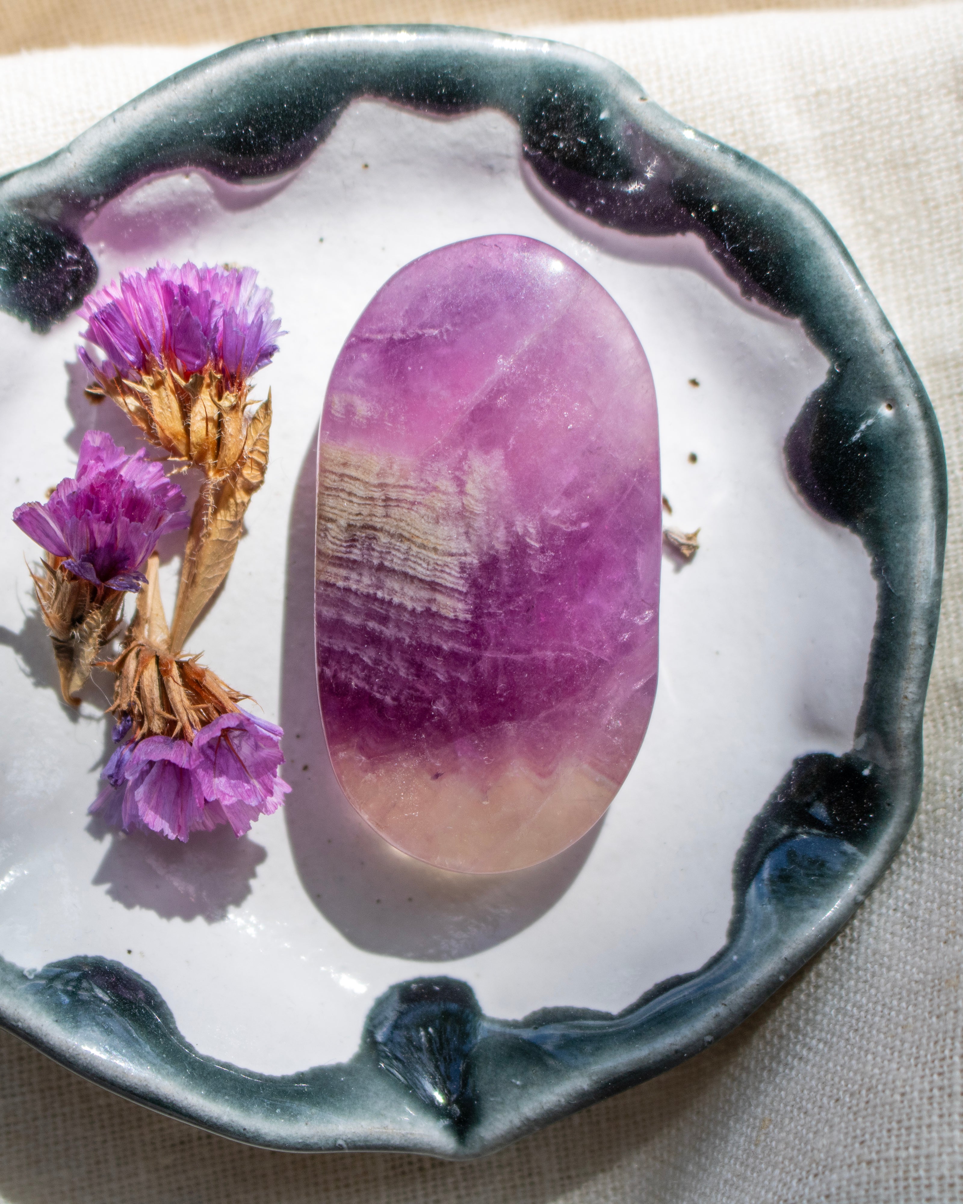 Purple crystal on a white dish with purple flowers