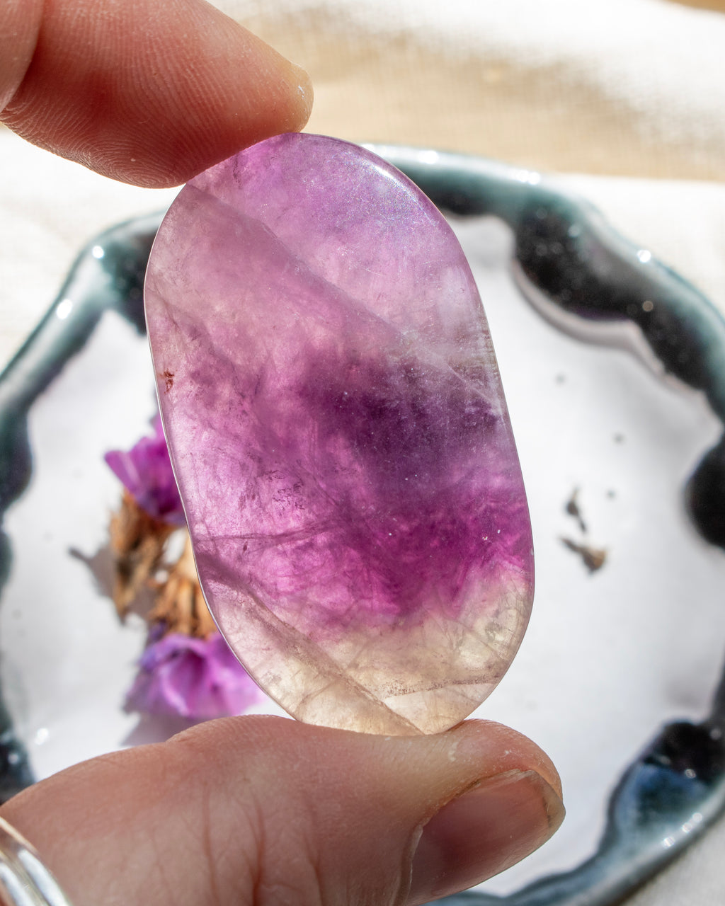 Hand holding a pink and purple crystal stone with a blurred background