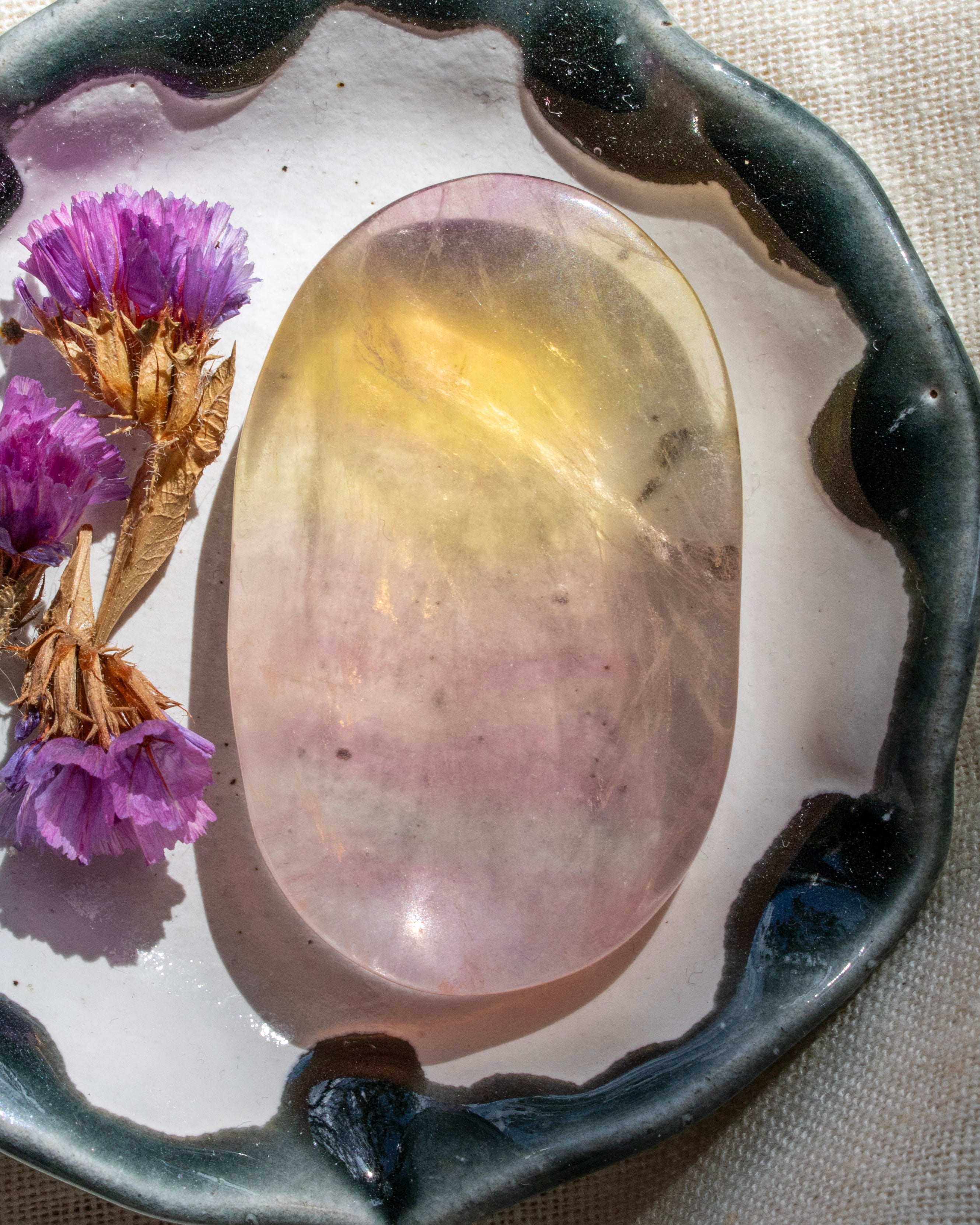 Translucent stone with purple flowers on a textured surface