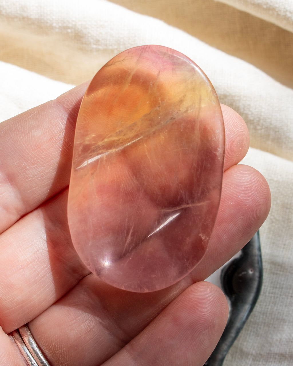 Hand holding a pink and orange stone against a neutral background