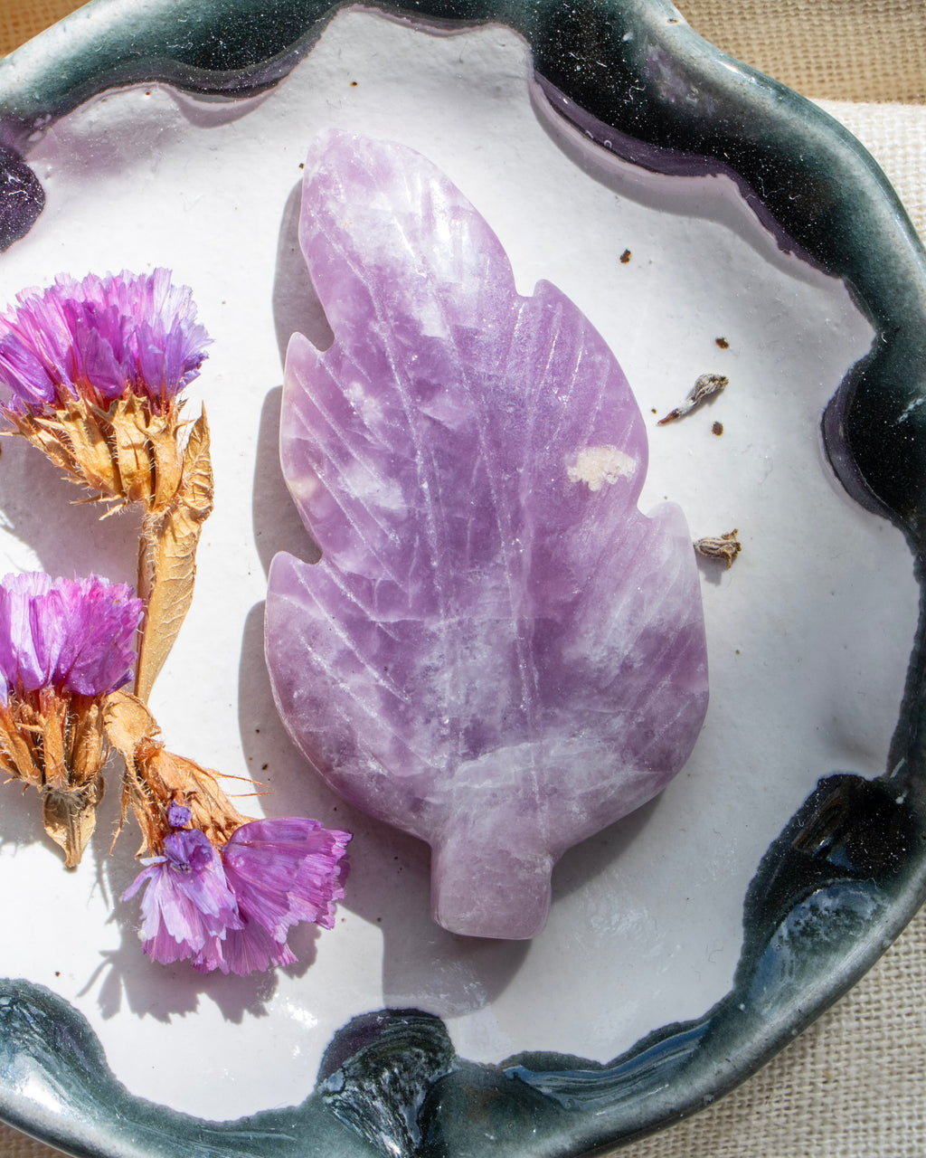 Purple leaf-shaped stone on a decorative plate with dried flowers