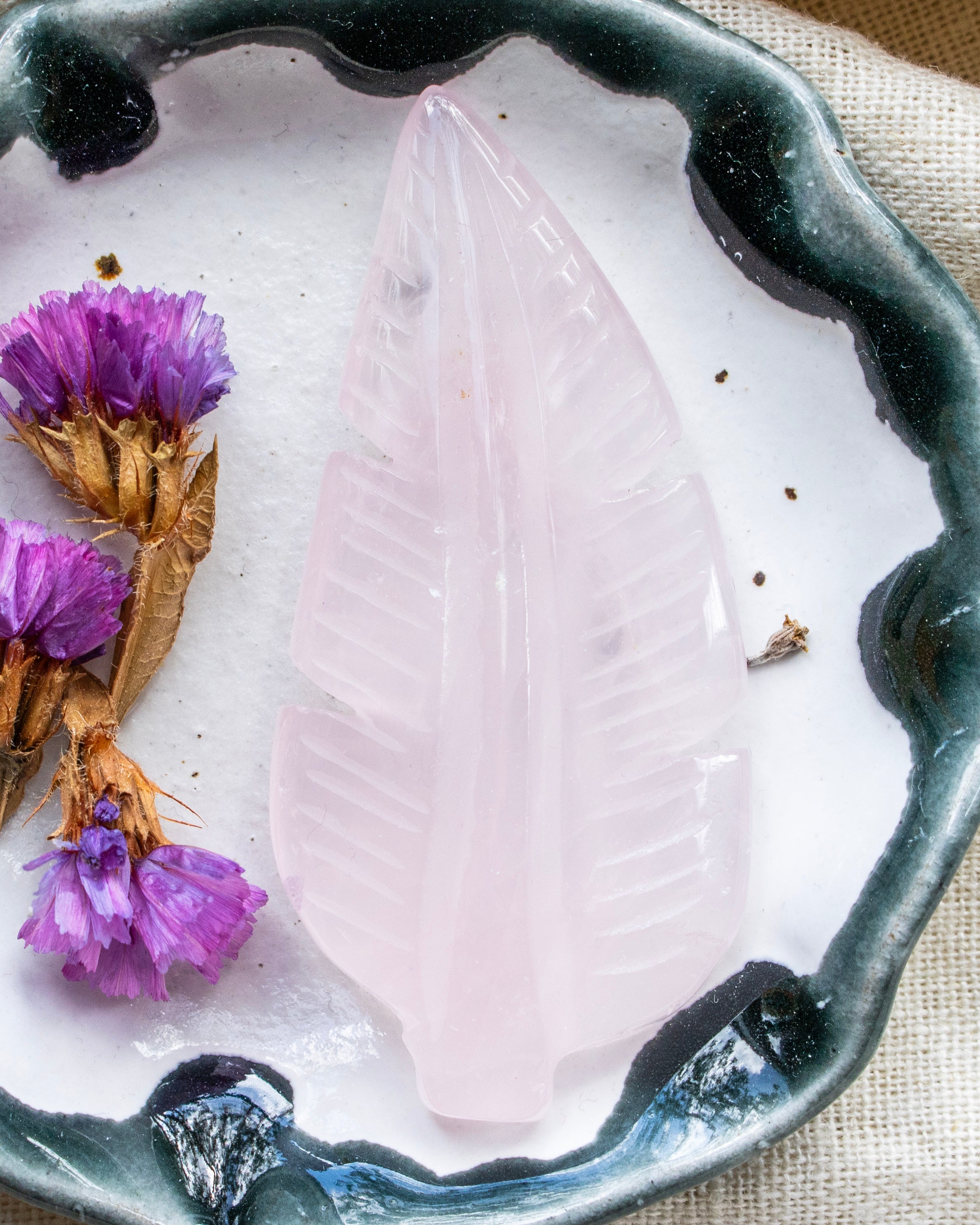 Crystal leaf on a white stone with purple flowers