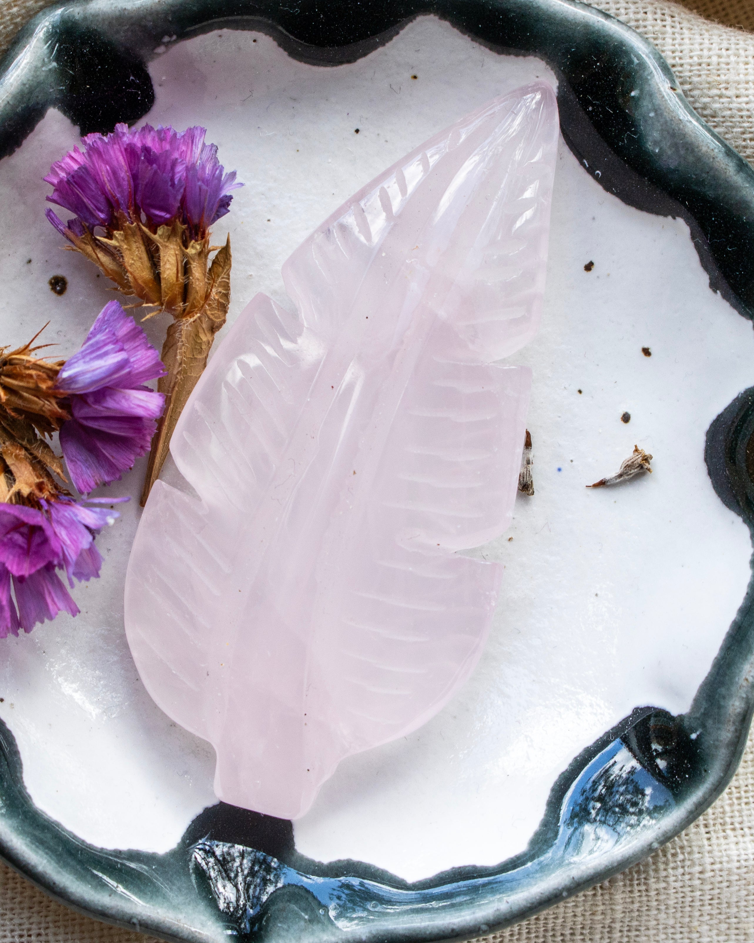 Decorative leaf-shaped stone on a white plate with purple flowers