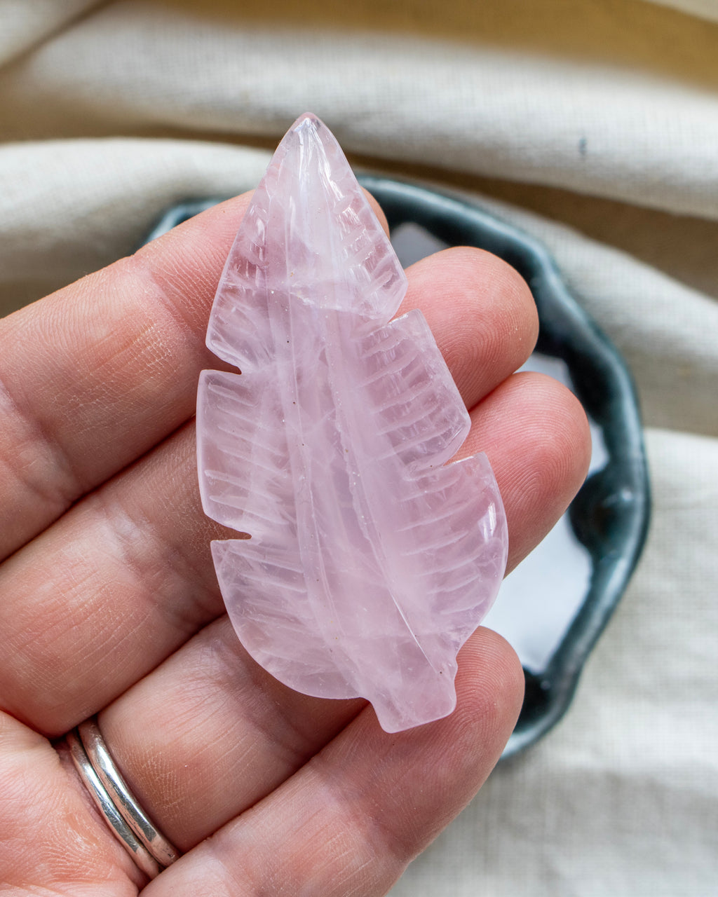 Pink crystal leaf held in a hand with a neutral background