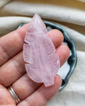 Pink crystal leaf held in a hand with a neutral background