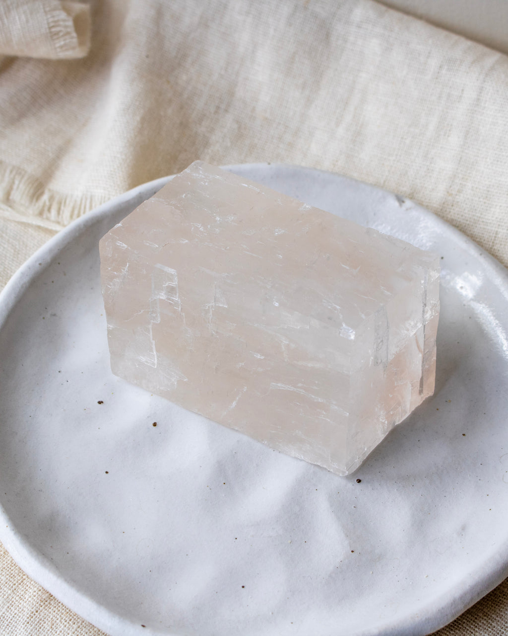 Crystal block on a white plate with a beige fabric background