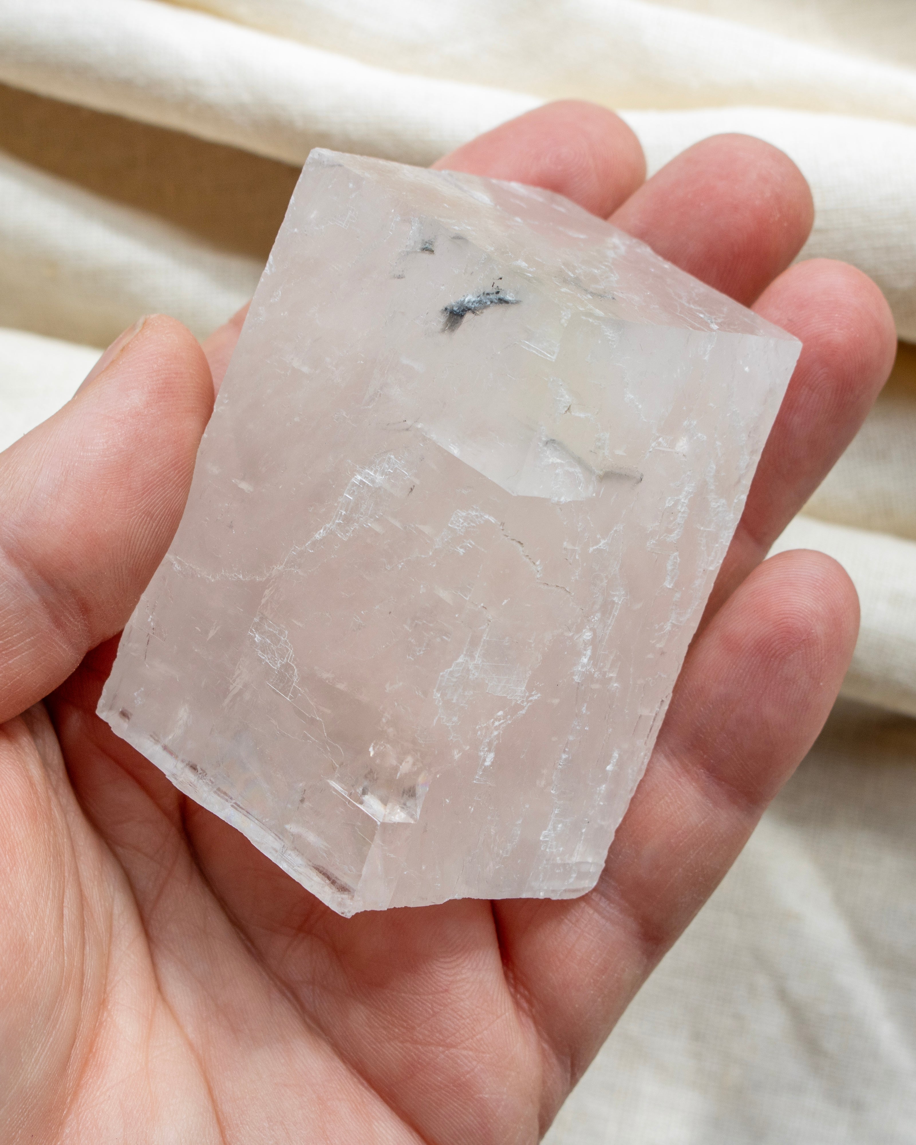 Clear crystal held in a hand with a soft background