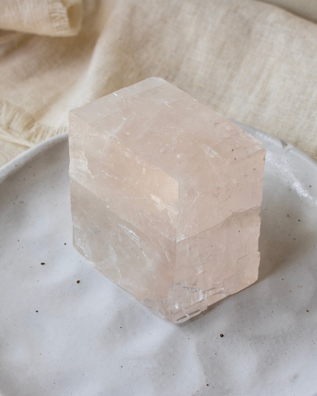Crystal cube on a textured surface with a soft fabric background