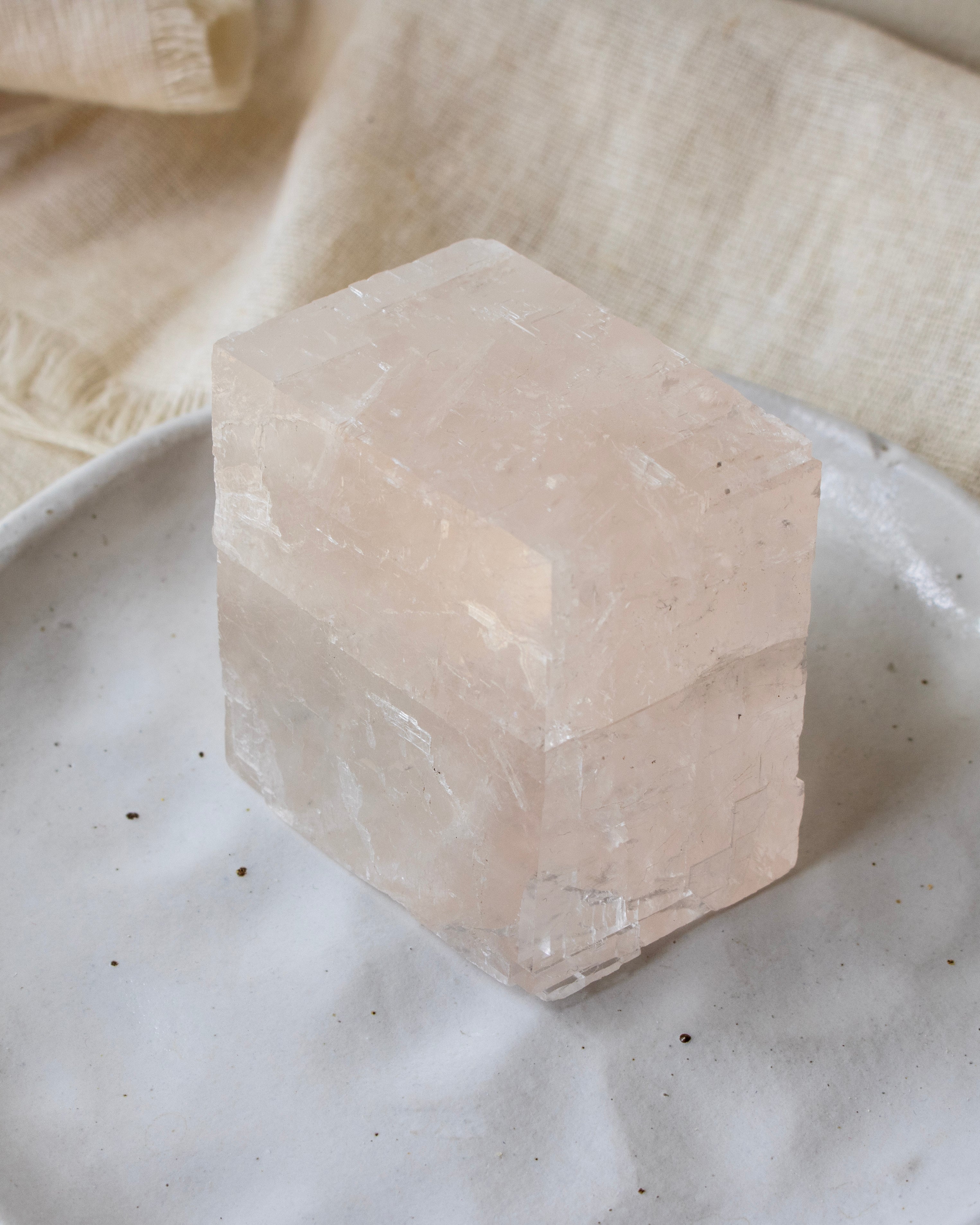 Crystal cube on a textured surface with a soft fabric background