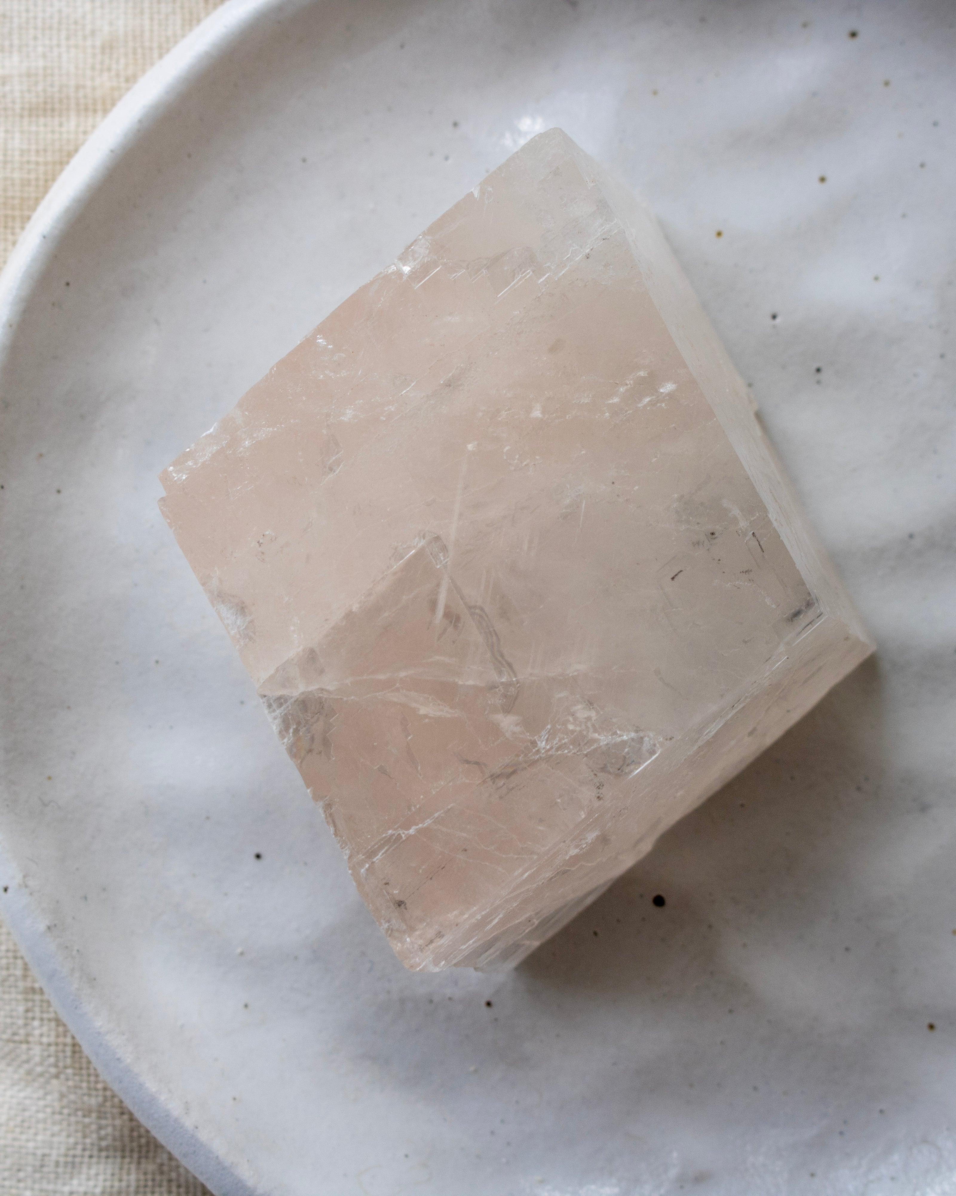 Square piece of beige stone on a speckled ceramic plate