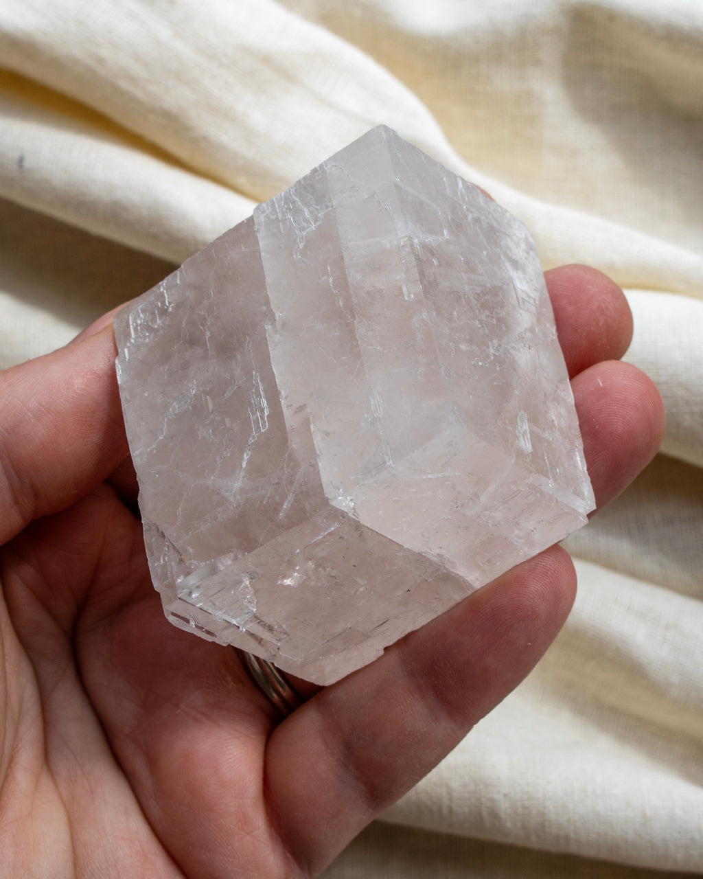 Hand holding a clear crystal against a neutral background