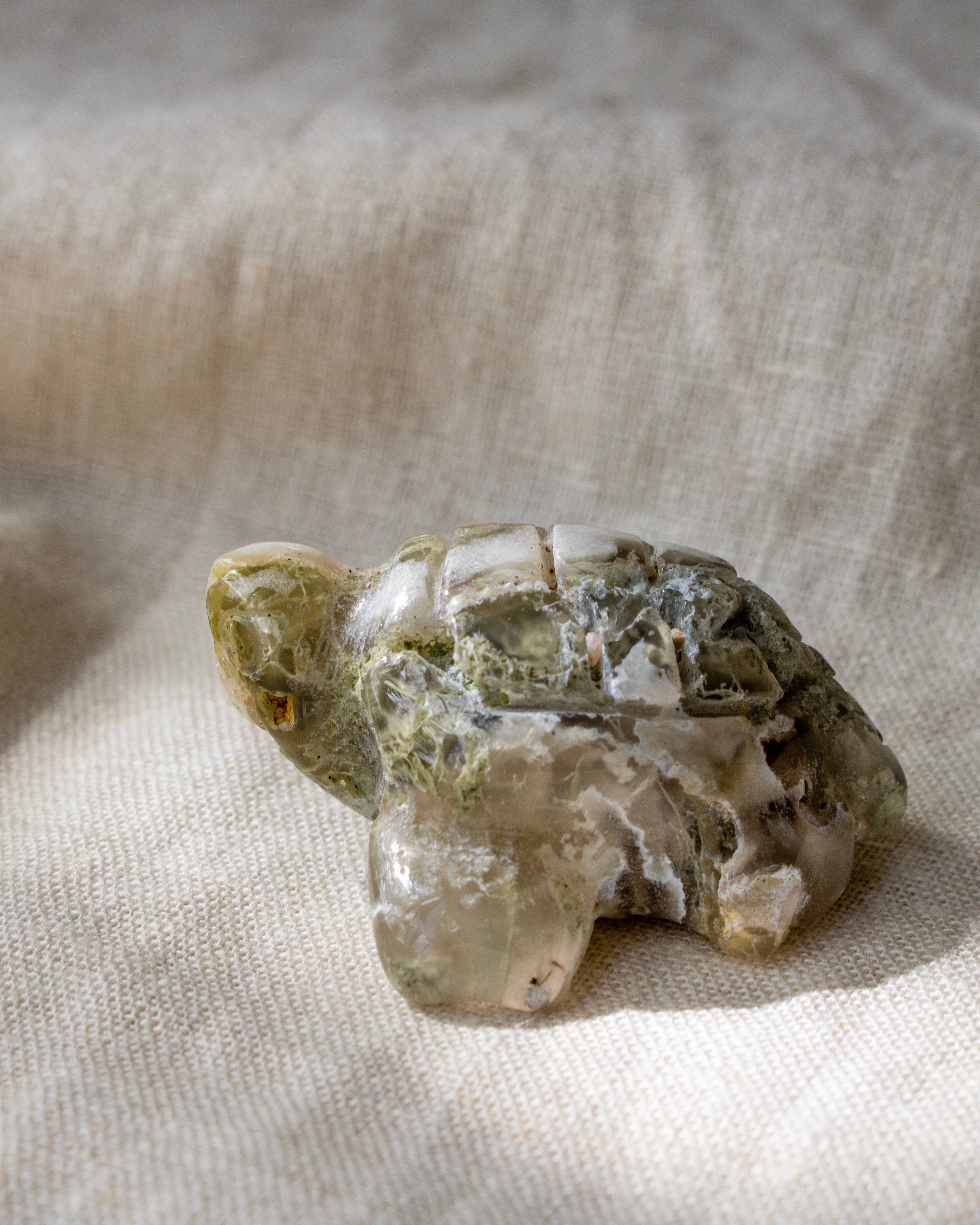 Crystal turtle figurine on a textured beige fabric background