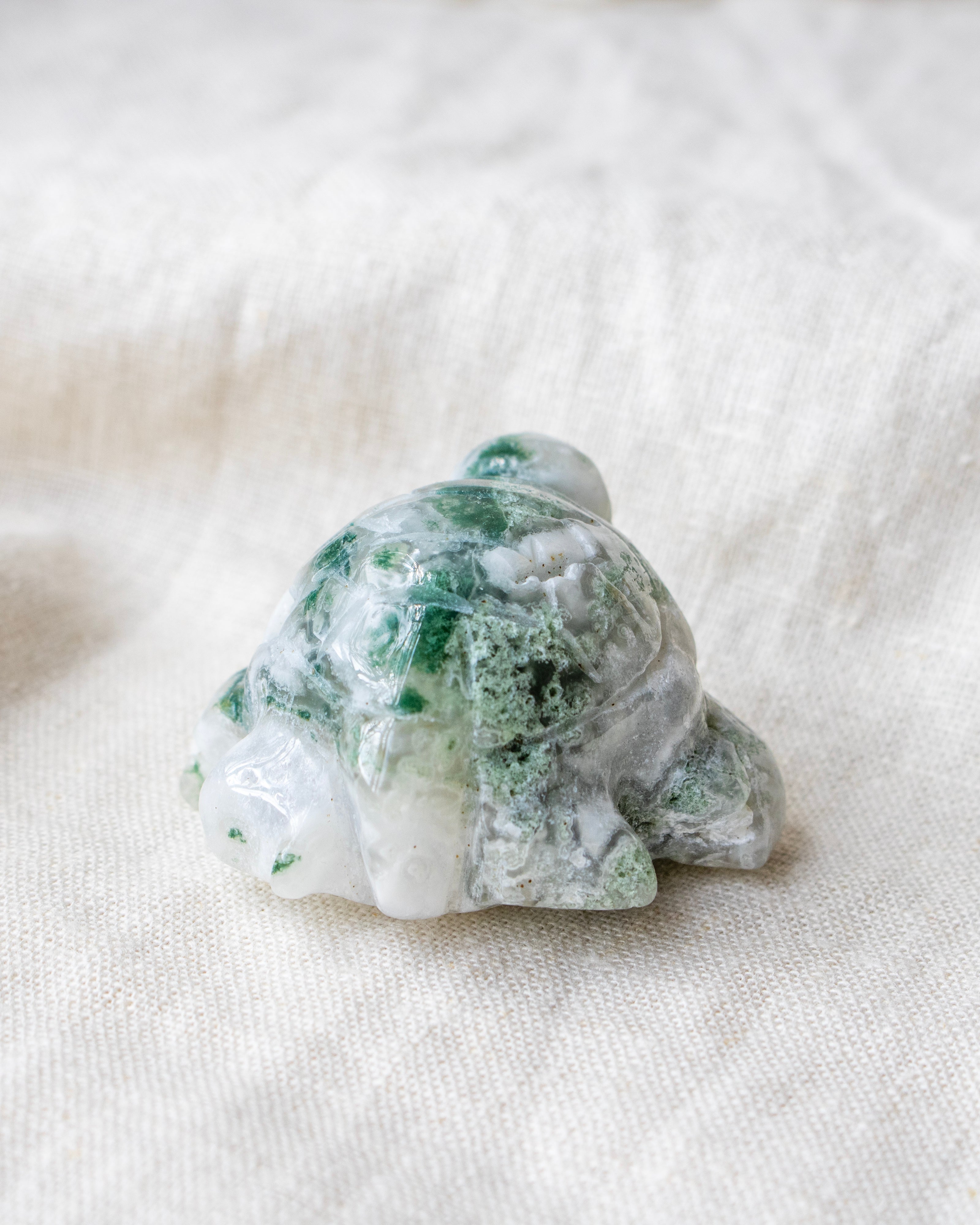 Carved stone turtle on a white fabric background