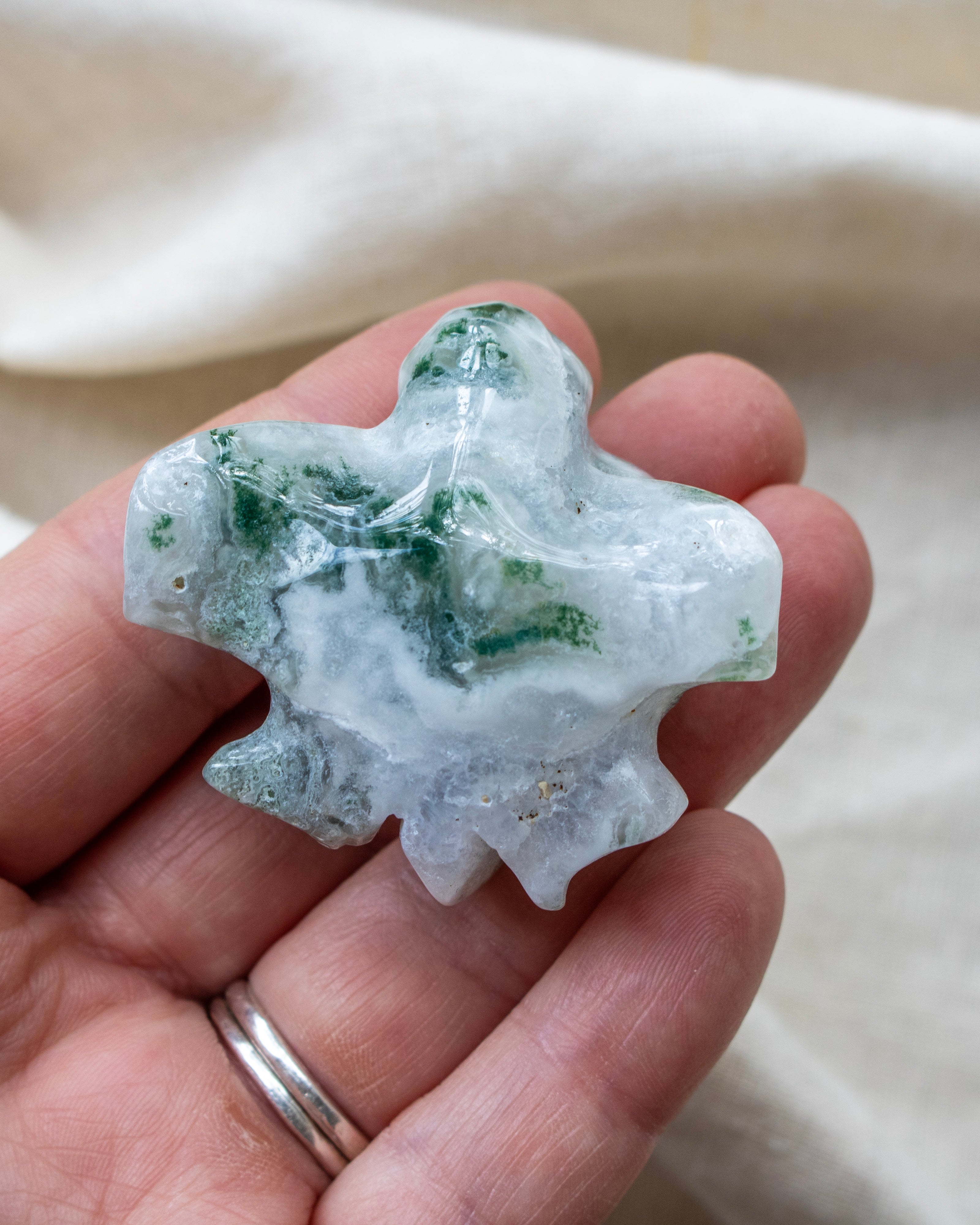 Hand holding a green and white crystal rock against a neutral background