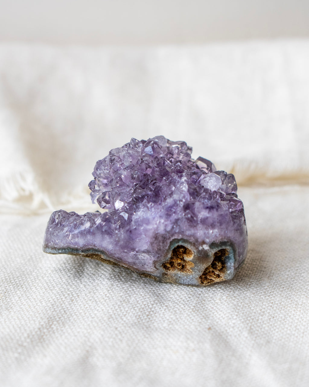 Amethyst crystal cluster on a white fabric background