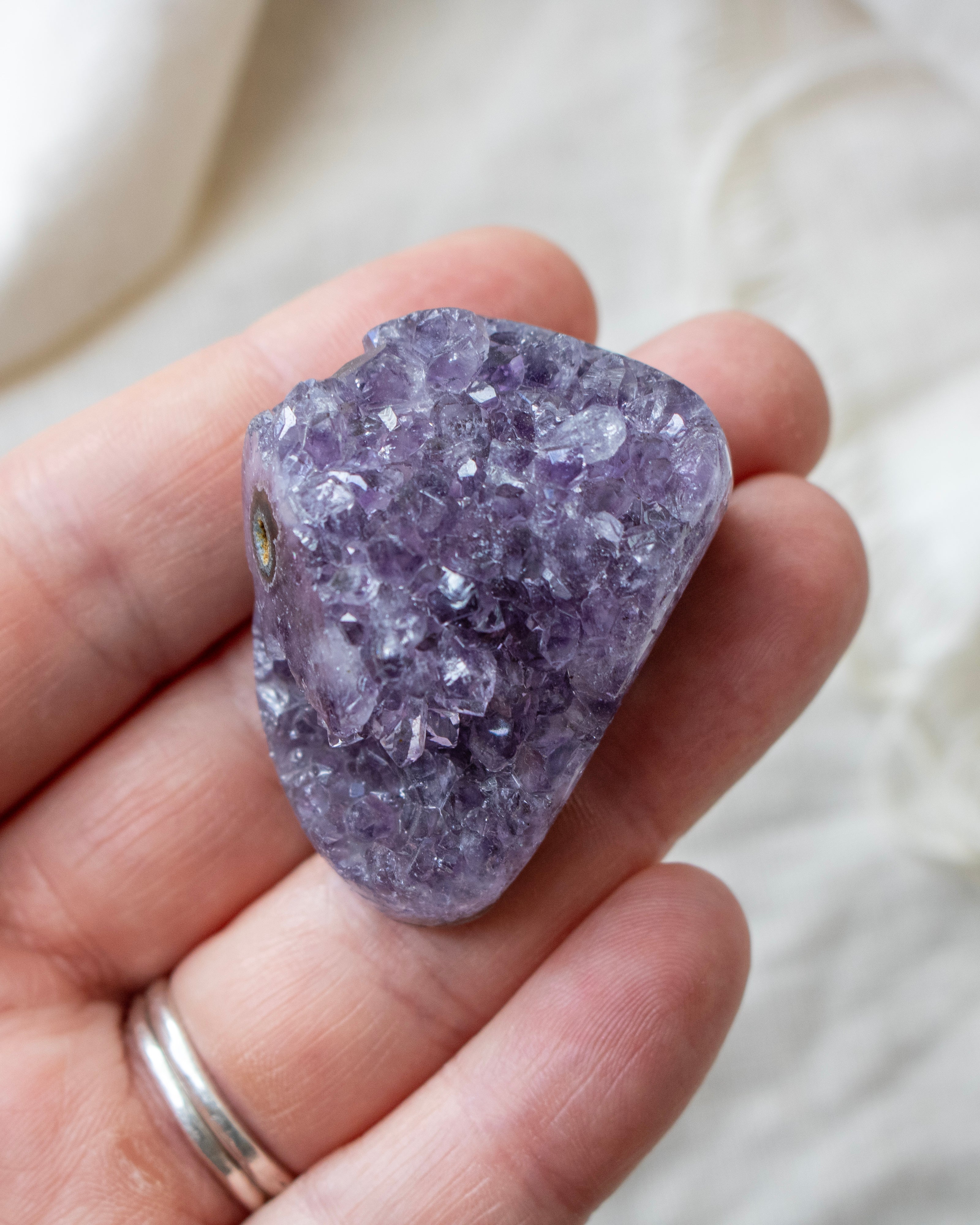 Hand holding a purple crystal rock against a blurred background