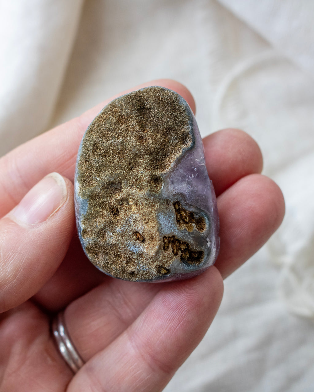 Hand holding a rough-textured stone with a neutral background