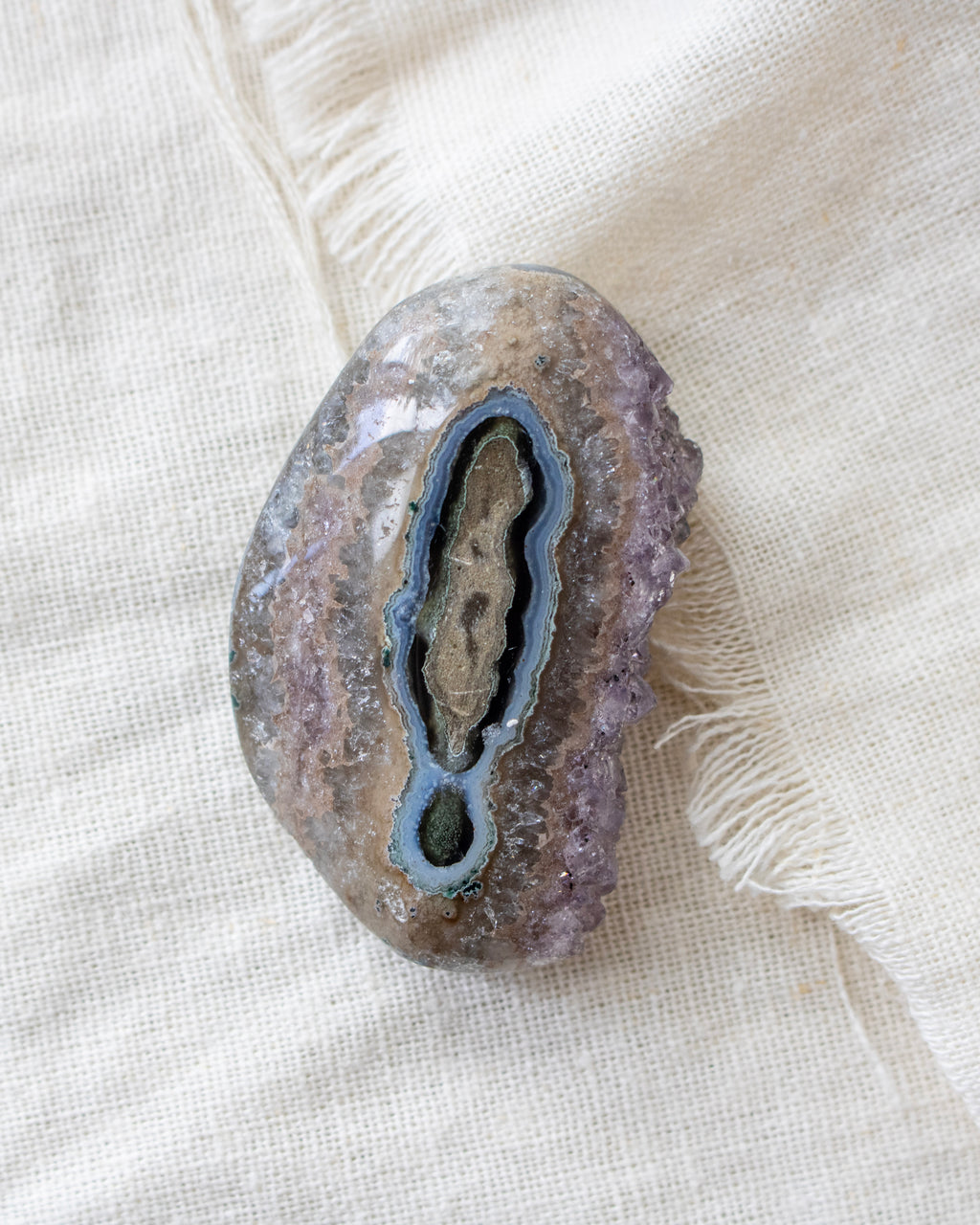 Geode crystal on a textured beige fabric background