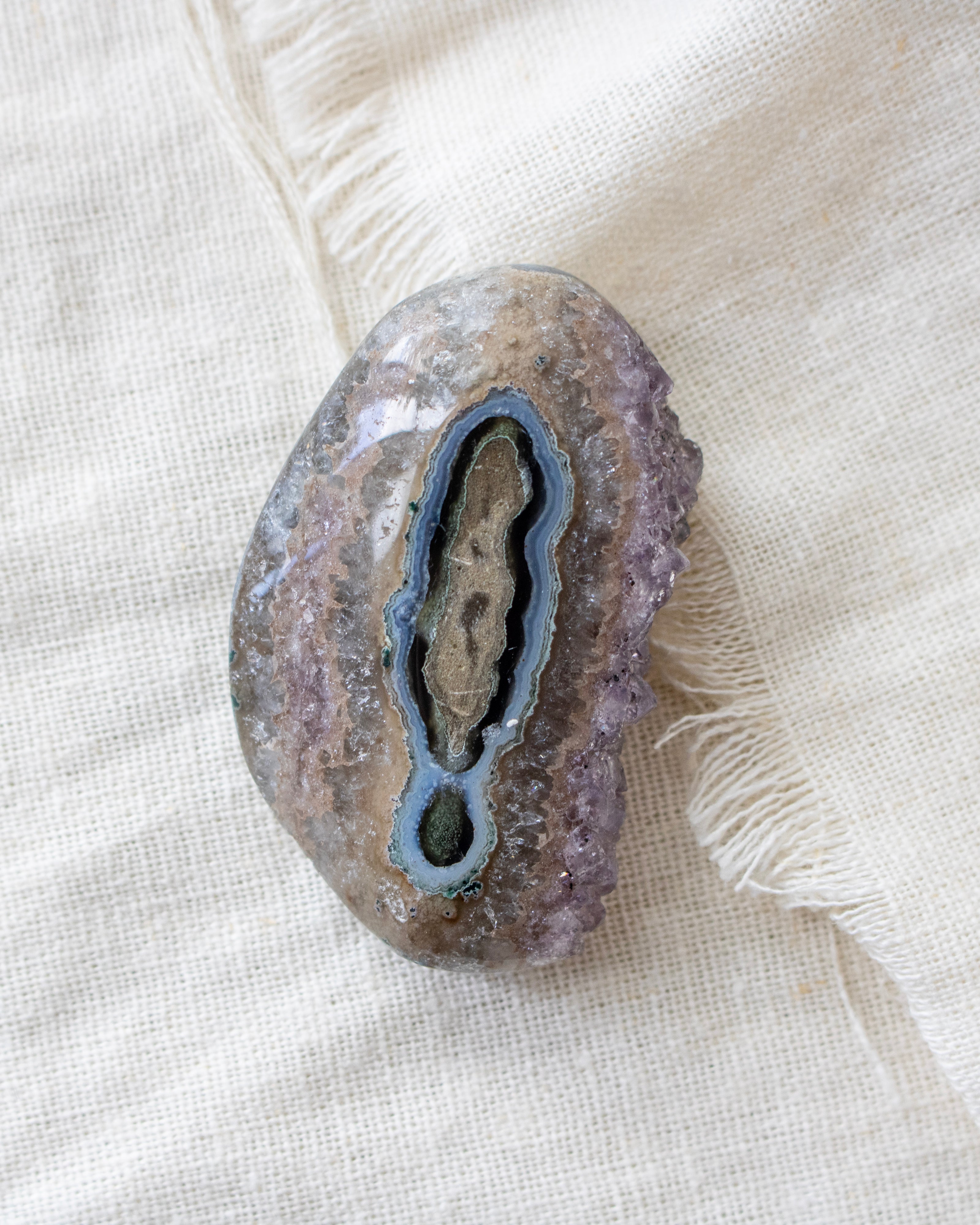 Geode crystal on a textured beige fabric background