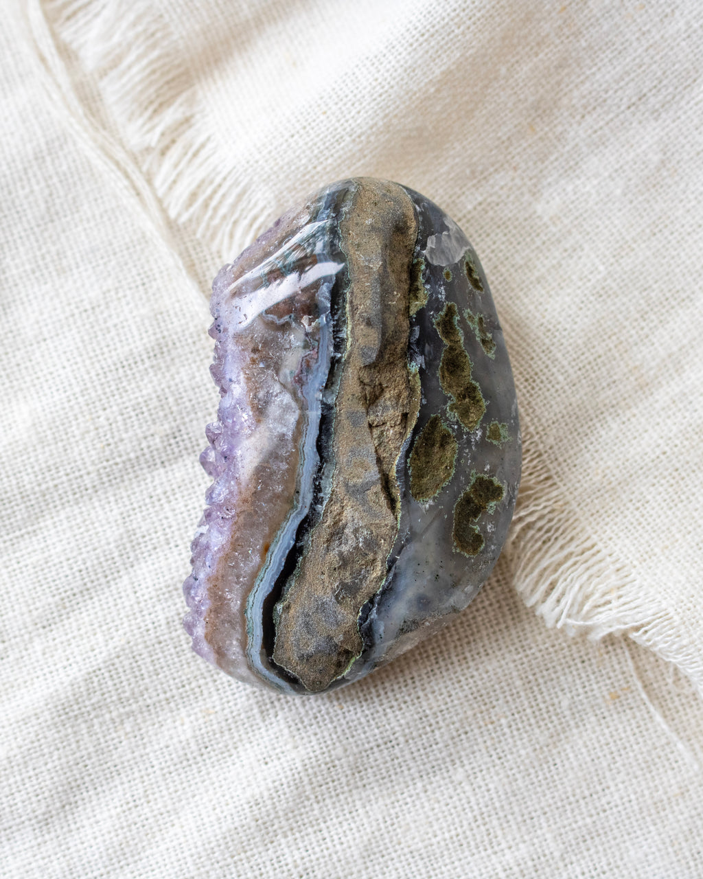 Geode crystal on a textured beige fabric background