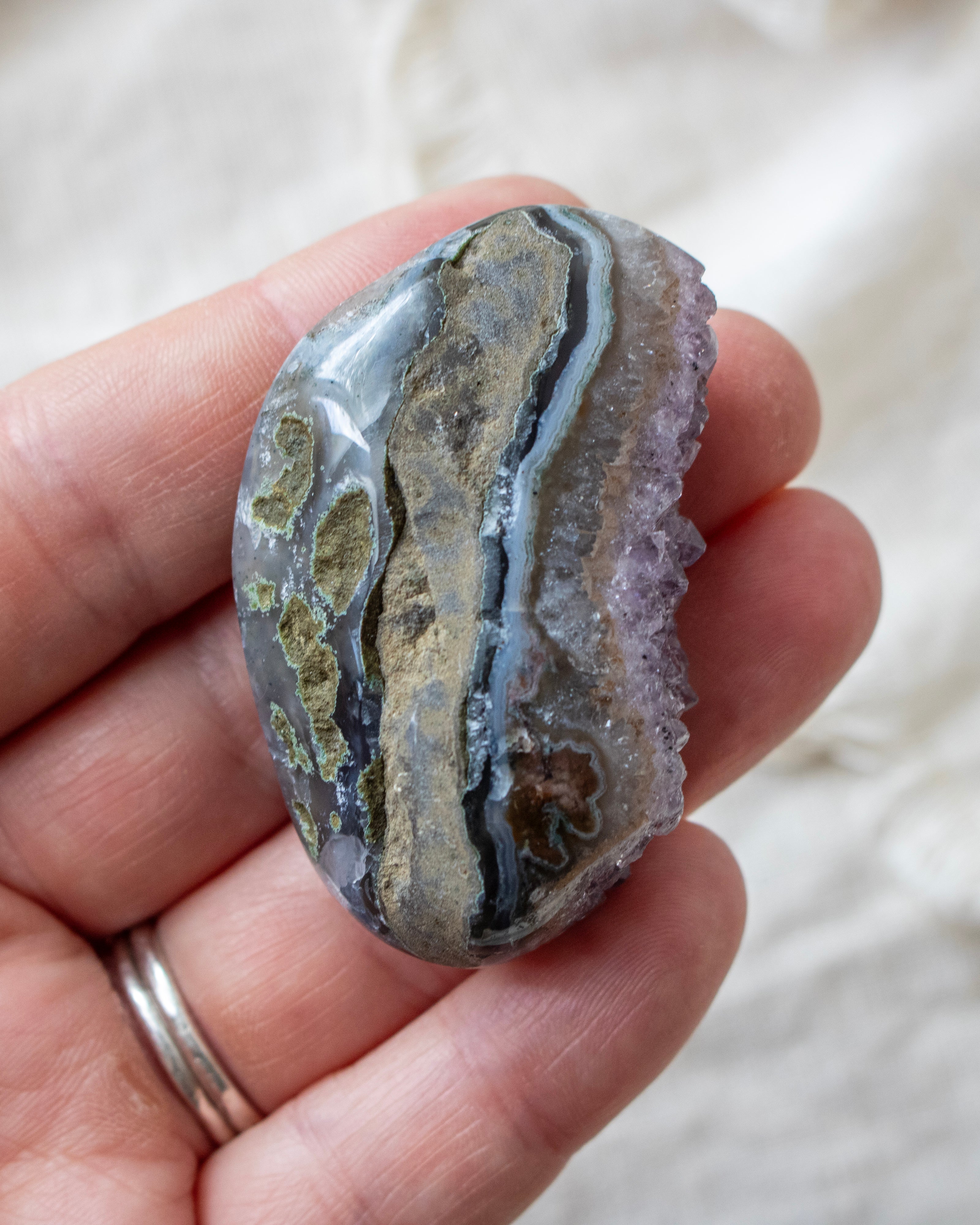 Hand holding a patterned stone with a blurred background