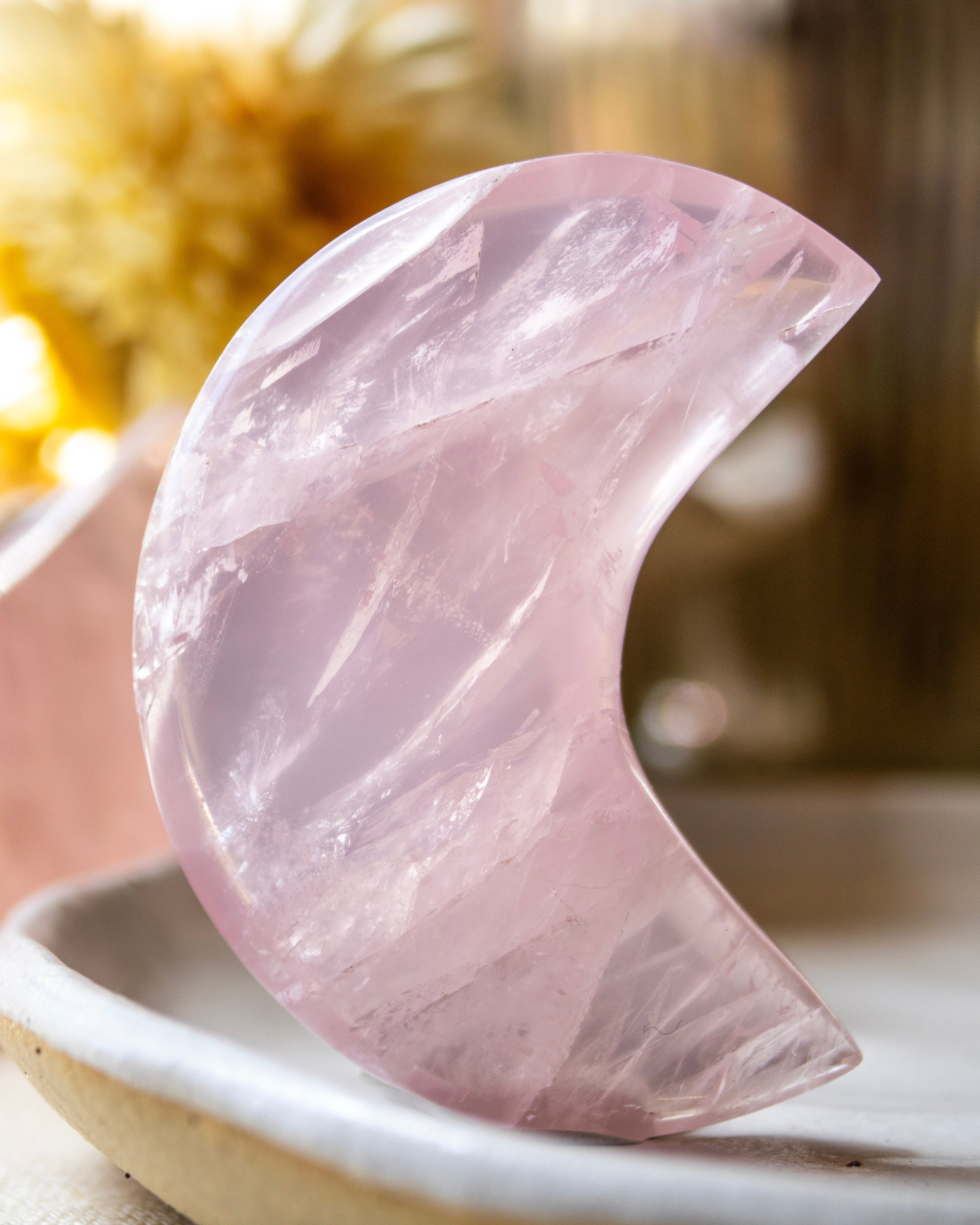 Pink crystal half-moon shape on a white plate with a blurred background