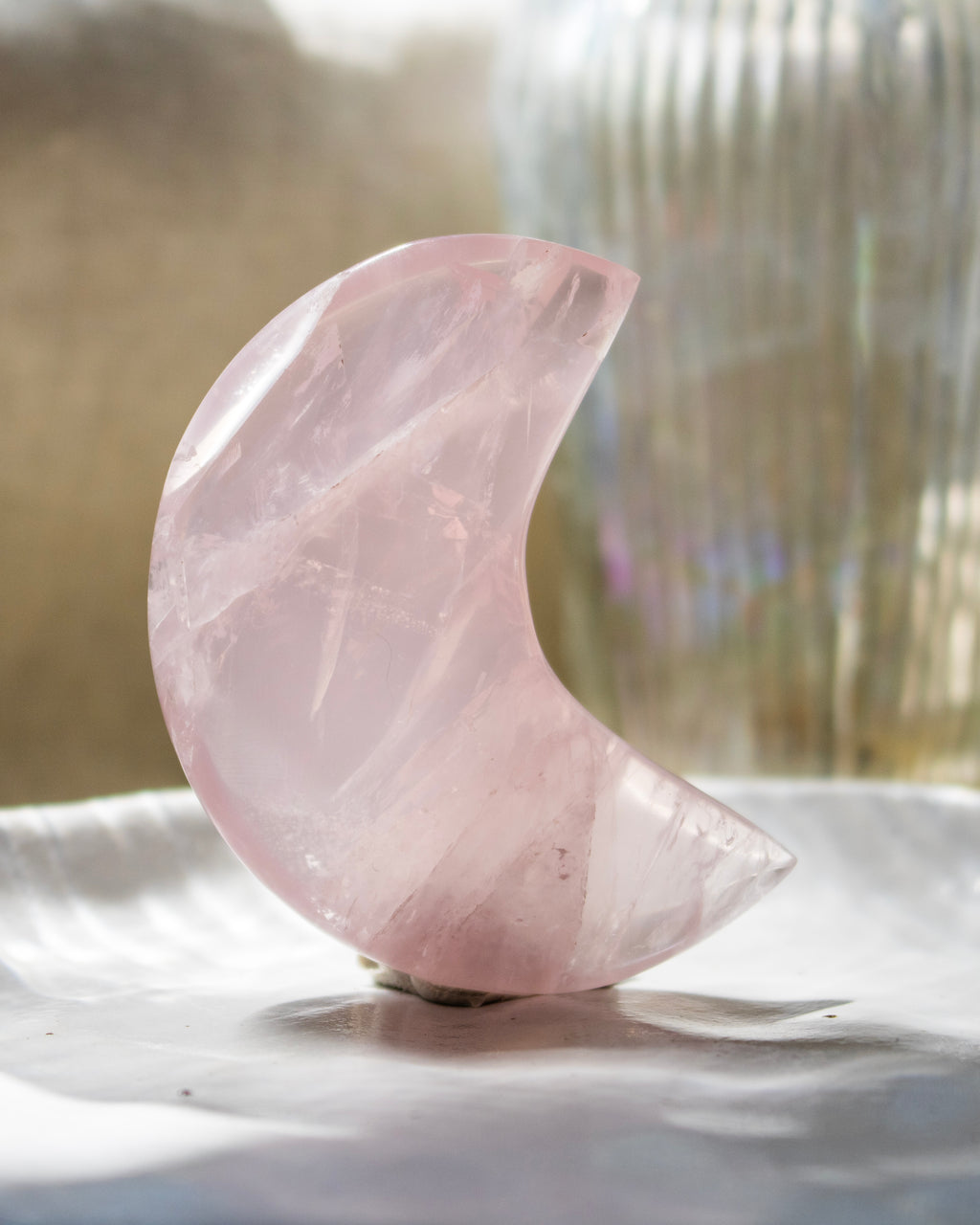 Pink crystal half-moon shape on a reflective surface with blurred background