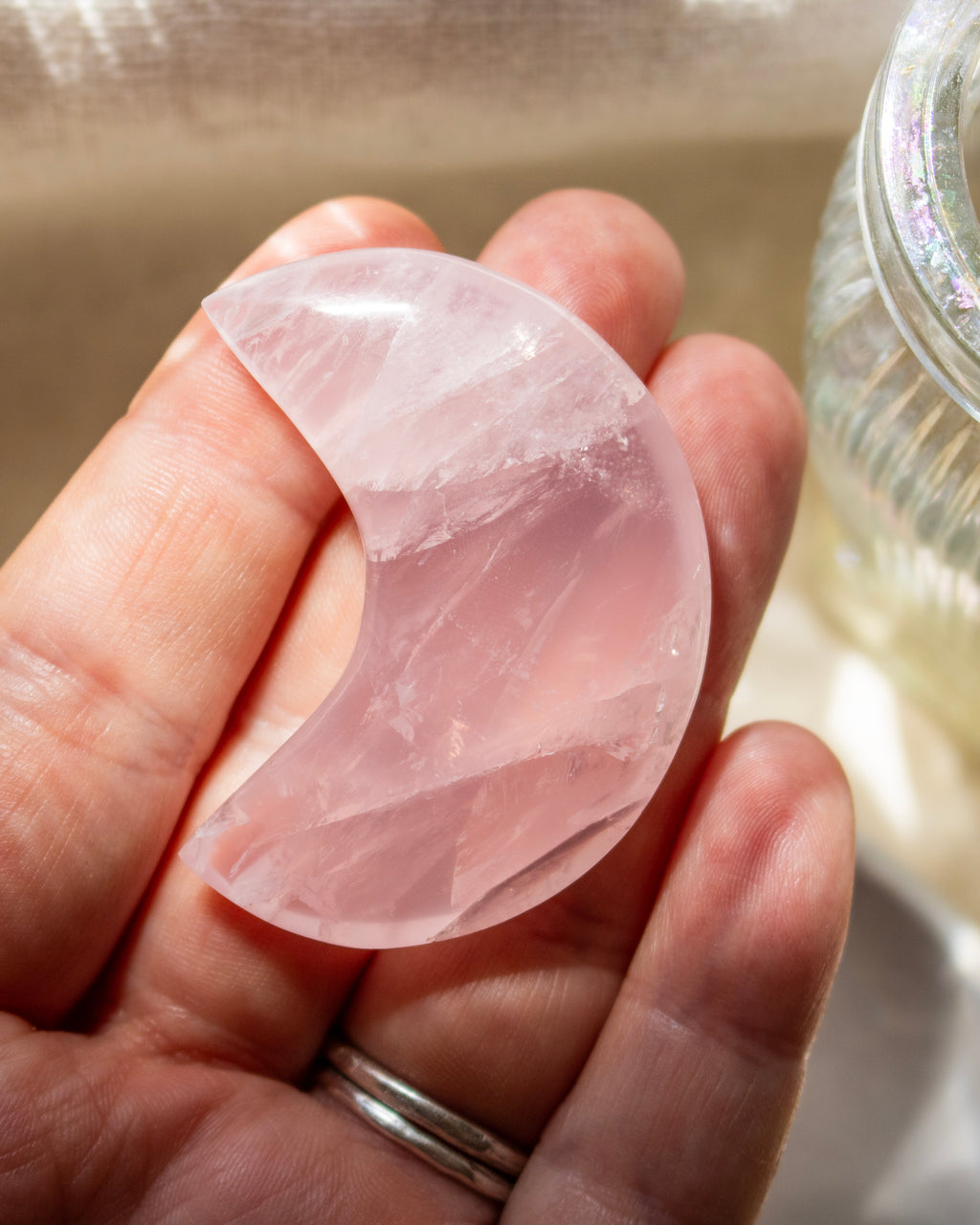 Hand holding a pink crystal with a blurred background