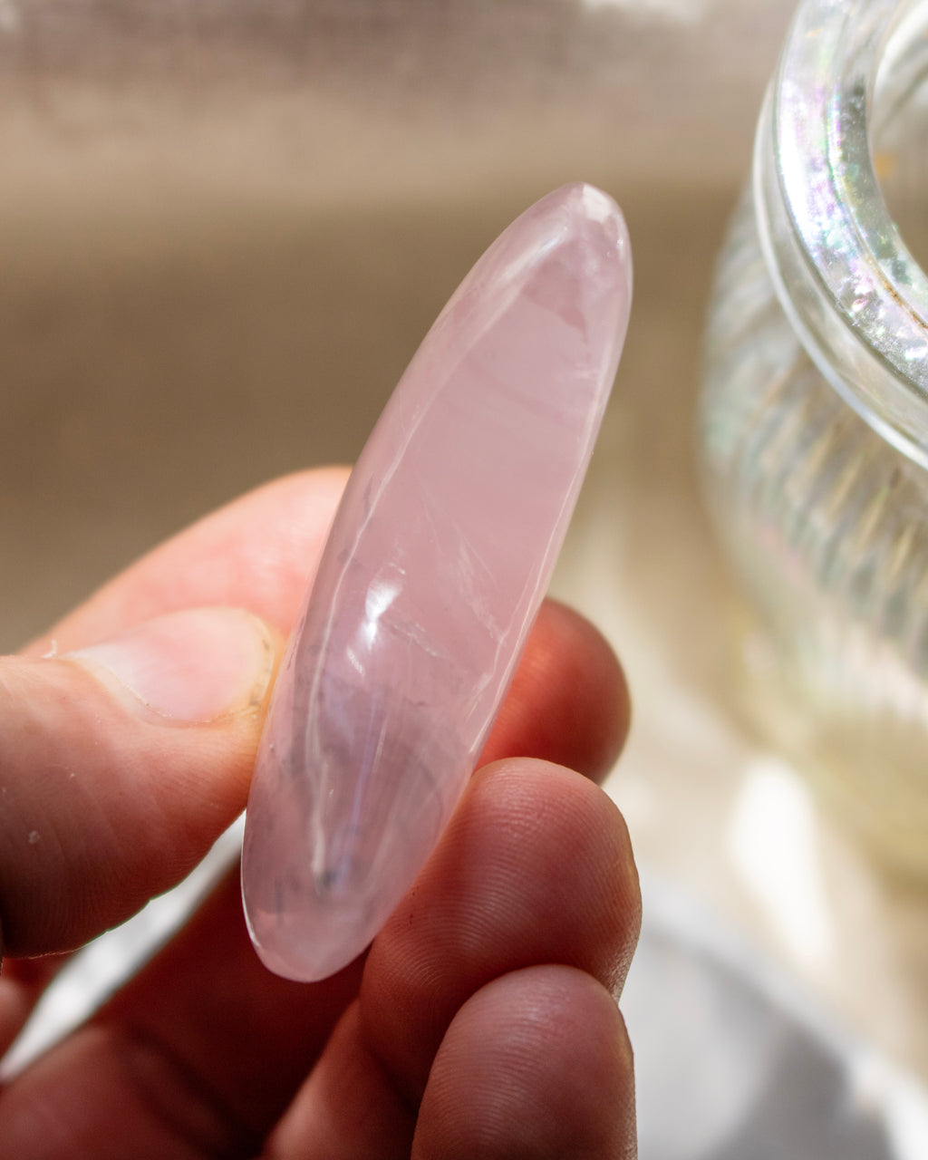 Clear crystal or gemstone held in a hand with a neutral background