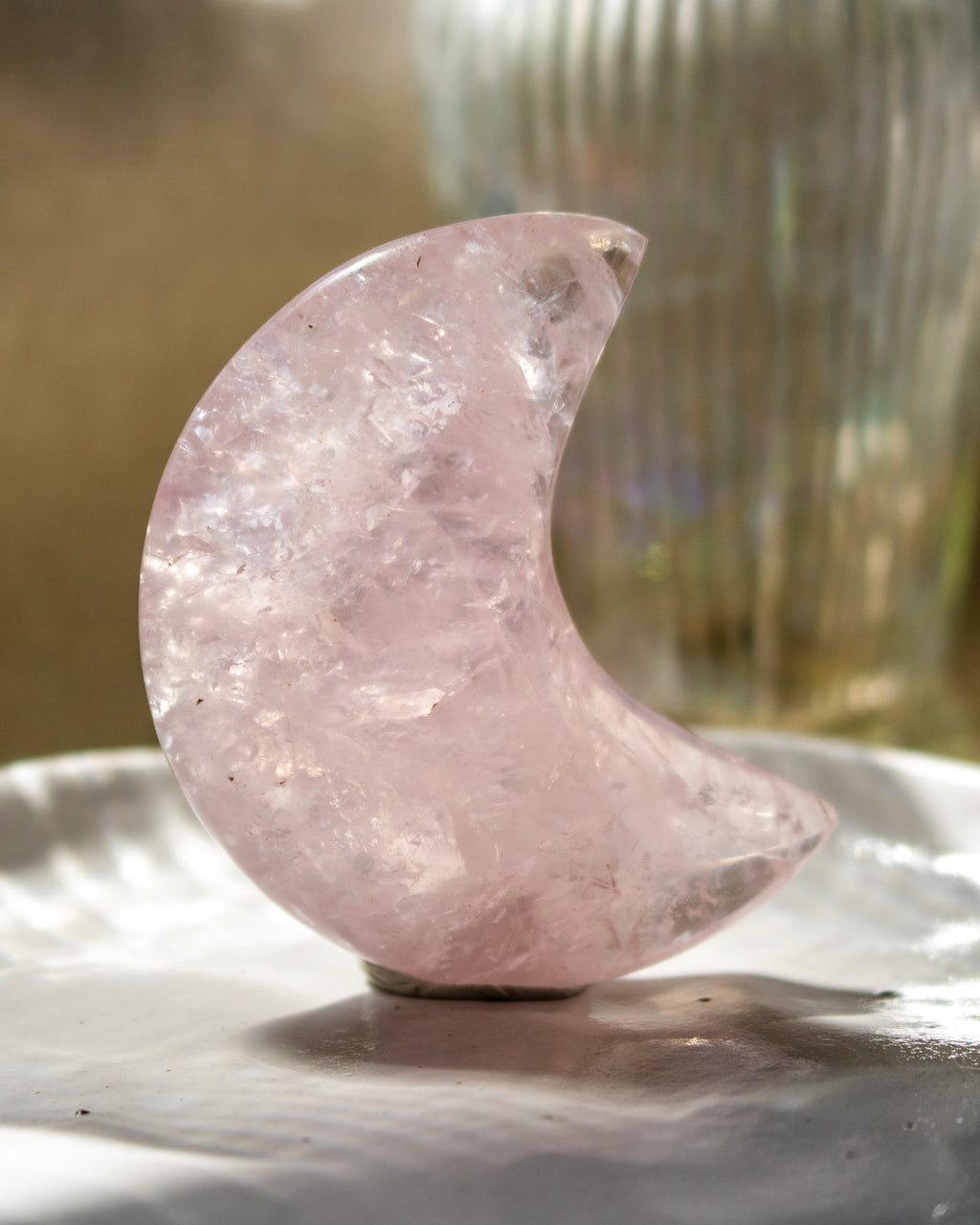 Pink crystal moon on a reflective surface with a blurred background