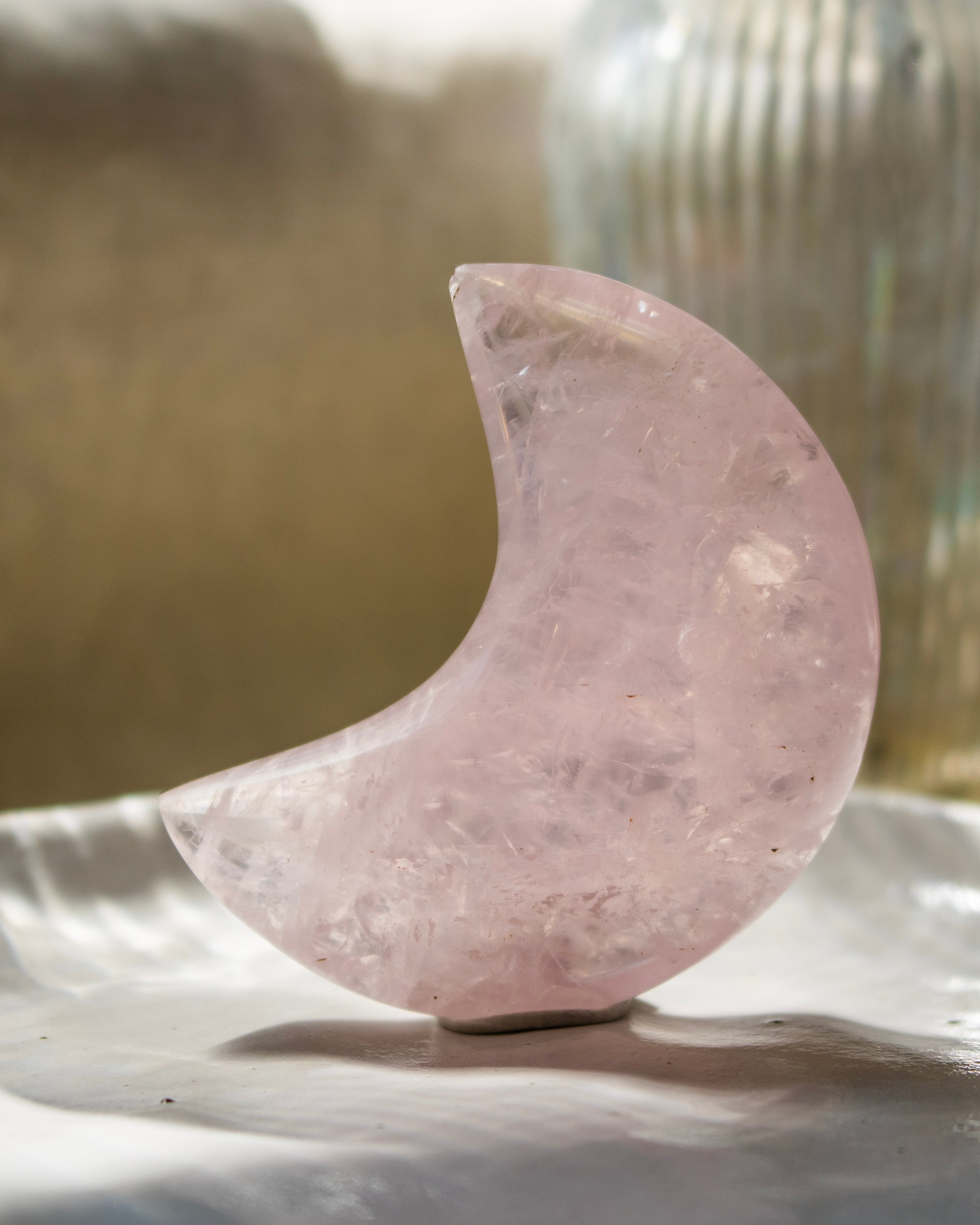 Pink crystal moon on a reflective surface with a blurred background