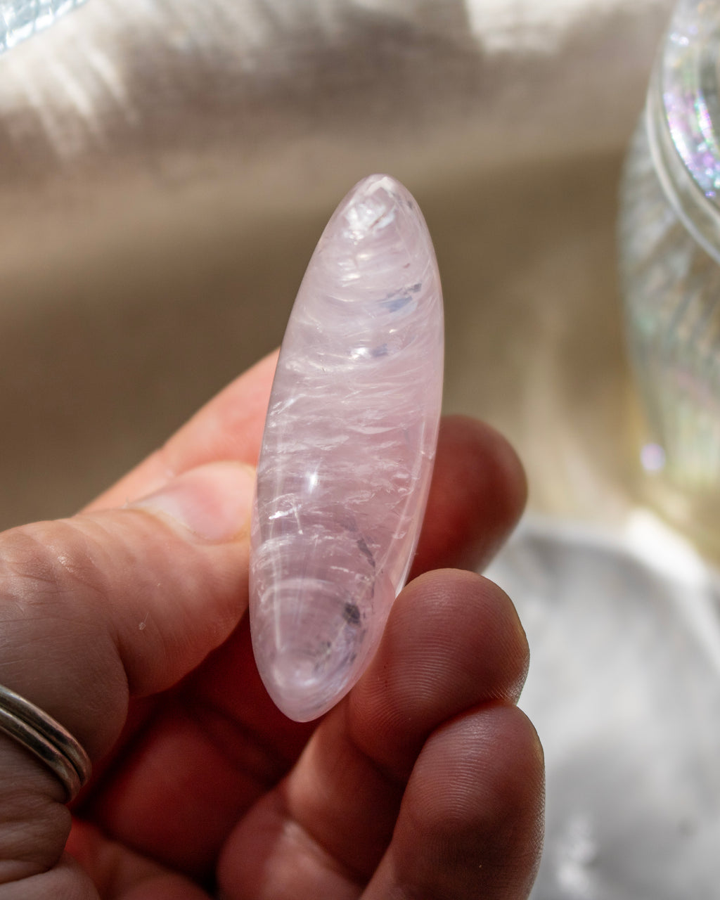 Clear crystal held in a hand with a blurred background