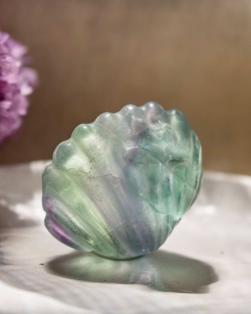 Translucent green and purple stone on a reflective surface with a blurred background