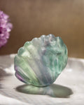 Translucent green and purple stone on a reflective surface with a blurred background