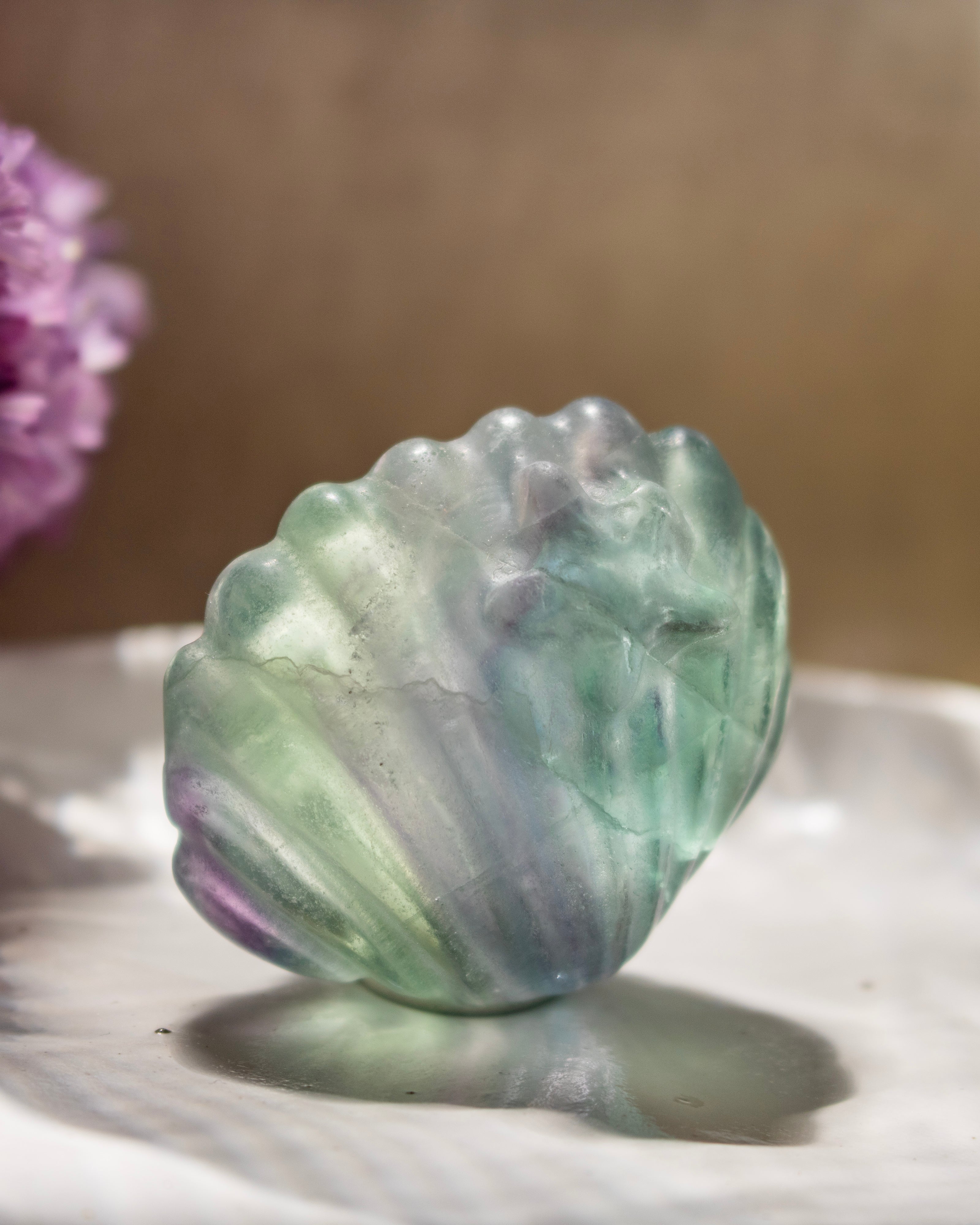 Translucent green and purple stone on a reflective surface with a blurred background