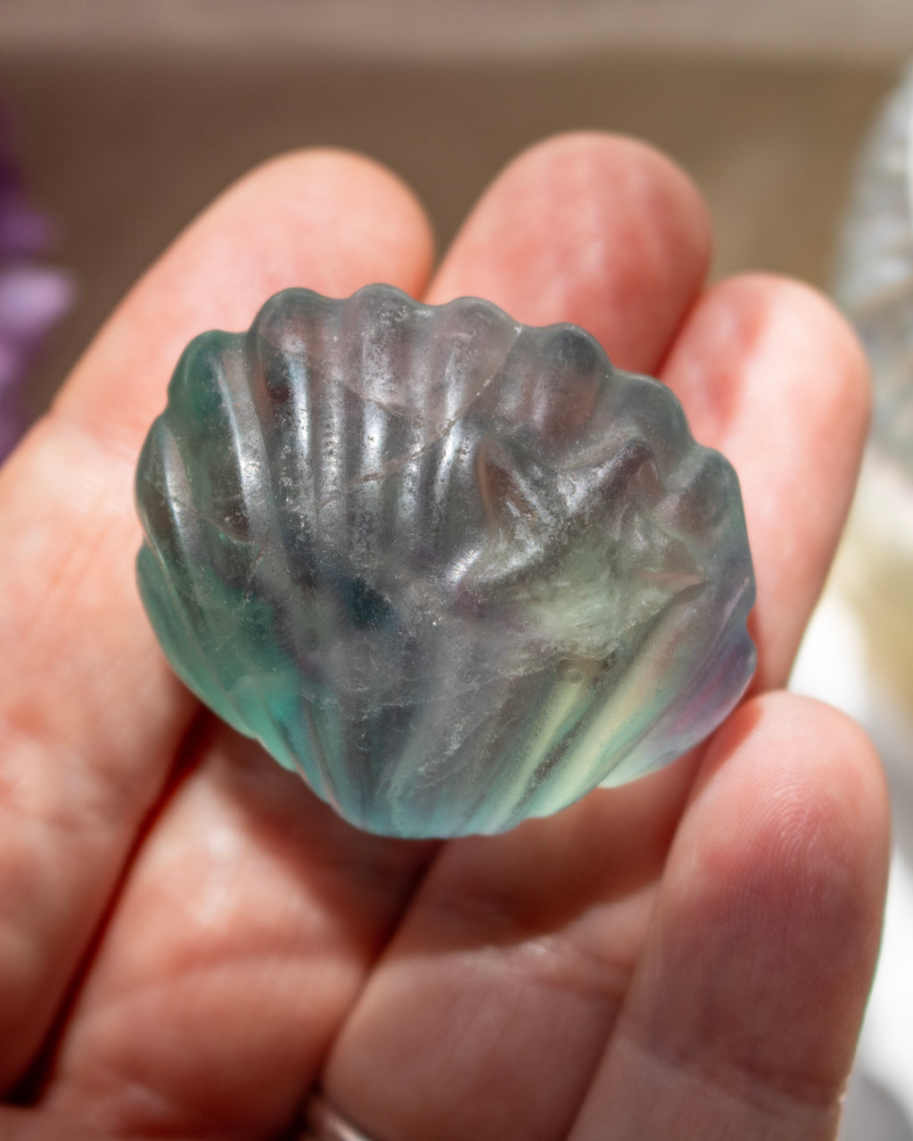 Transparent green stone with shell design held in a hand