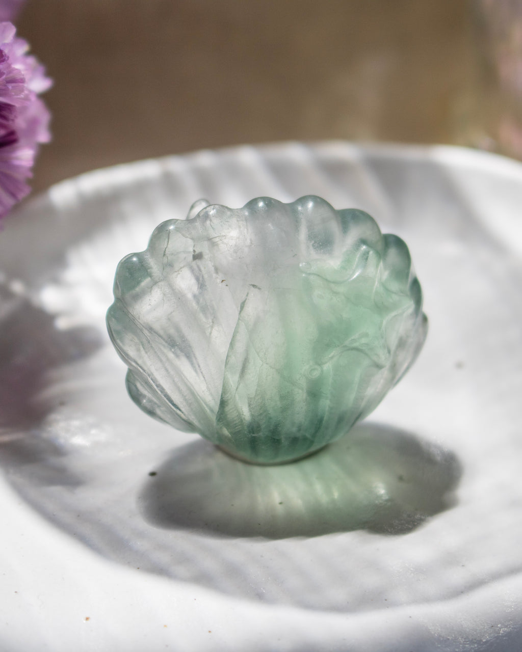 Green crystal carving on a white surface with a blurred background