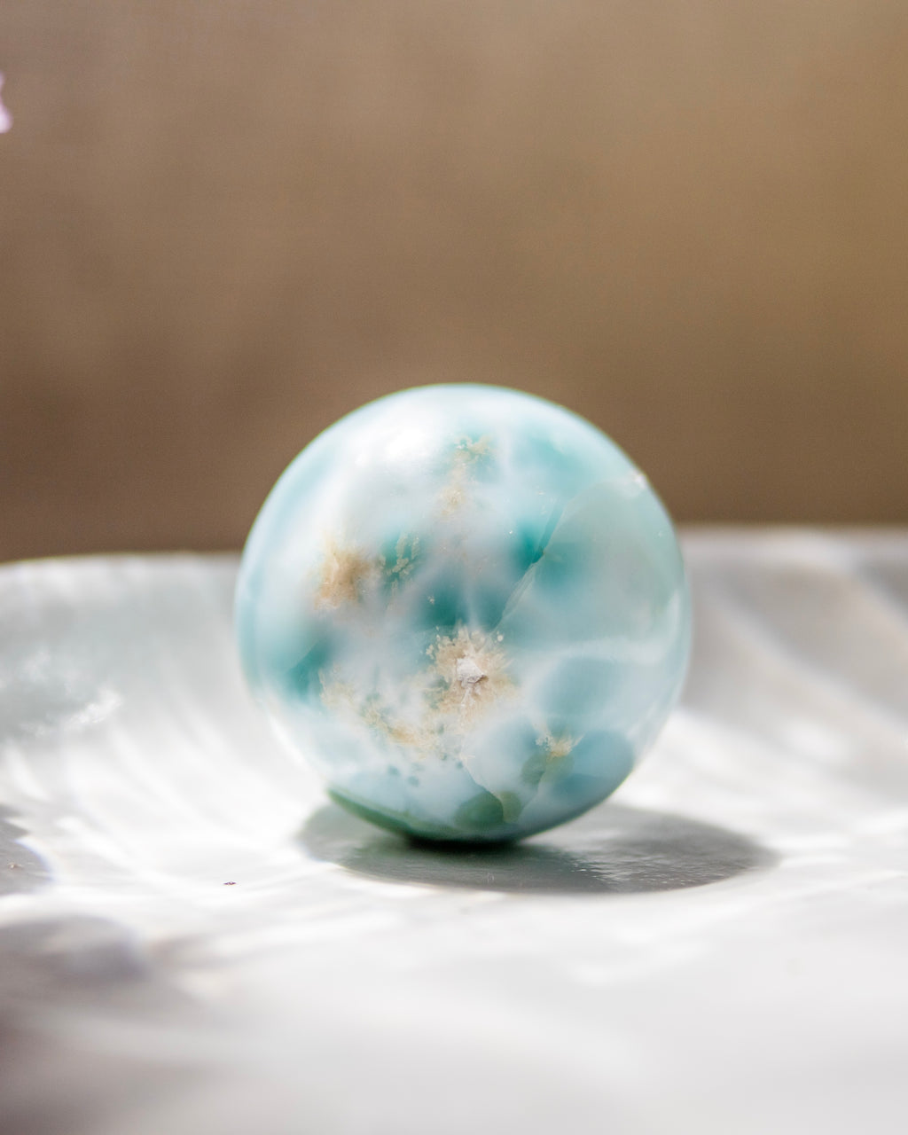 Marble-like sphere with blue and white patterns on a reflective surface