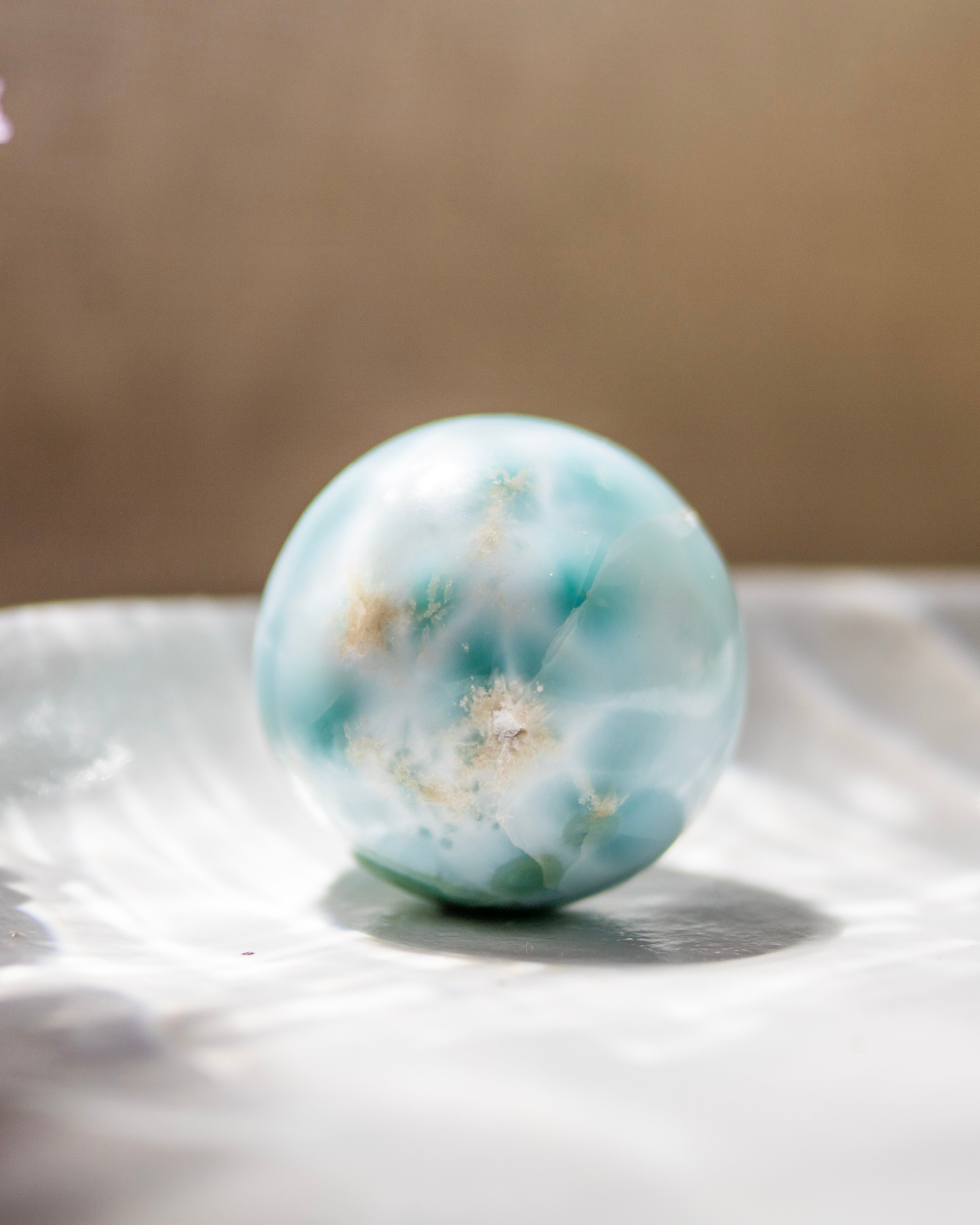 Marble-like sphere with blue and white patterns on a reflective surface