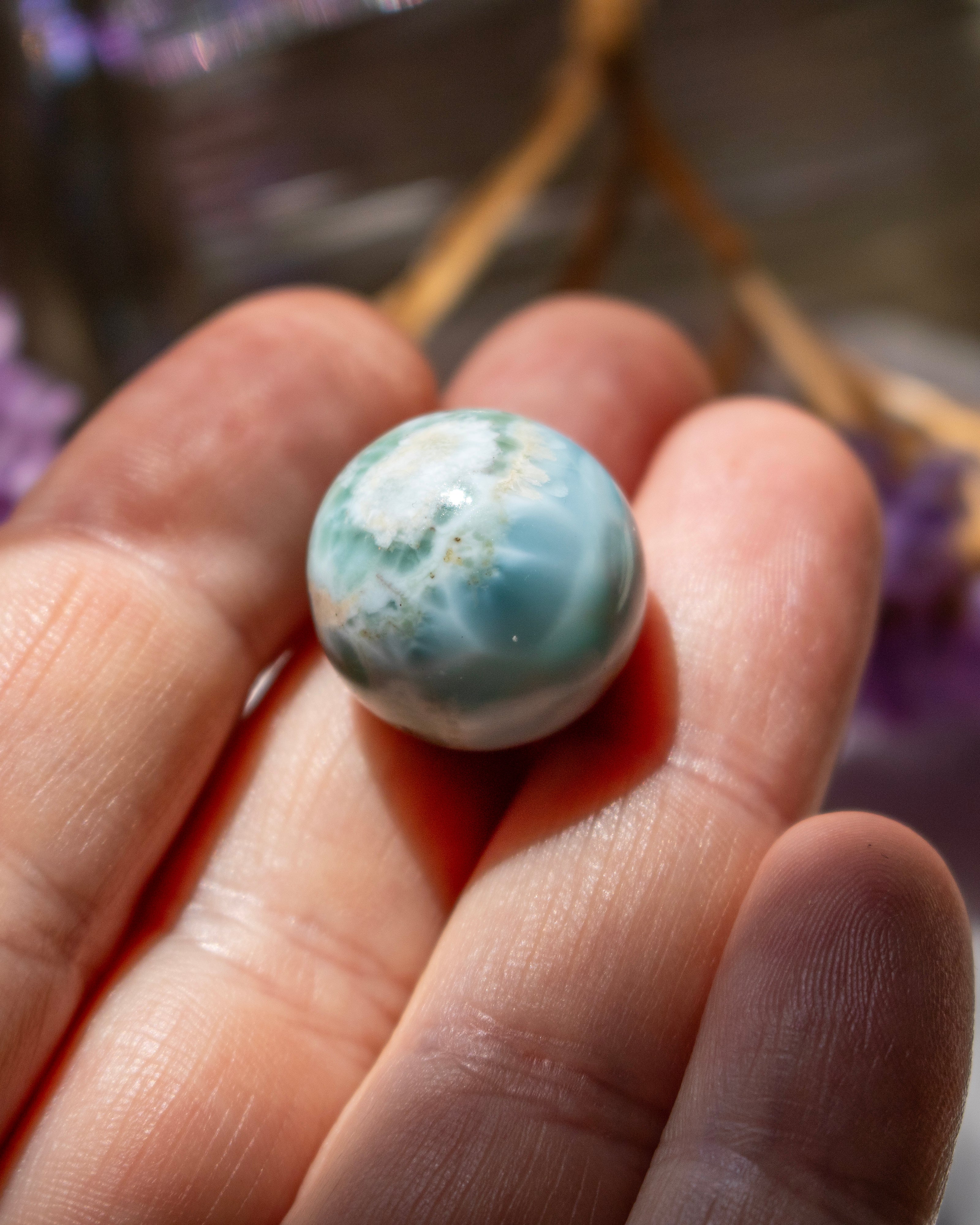 Marble-like sphere held between fingers with a blurred background