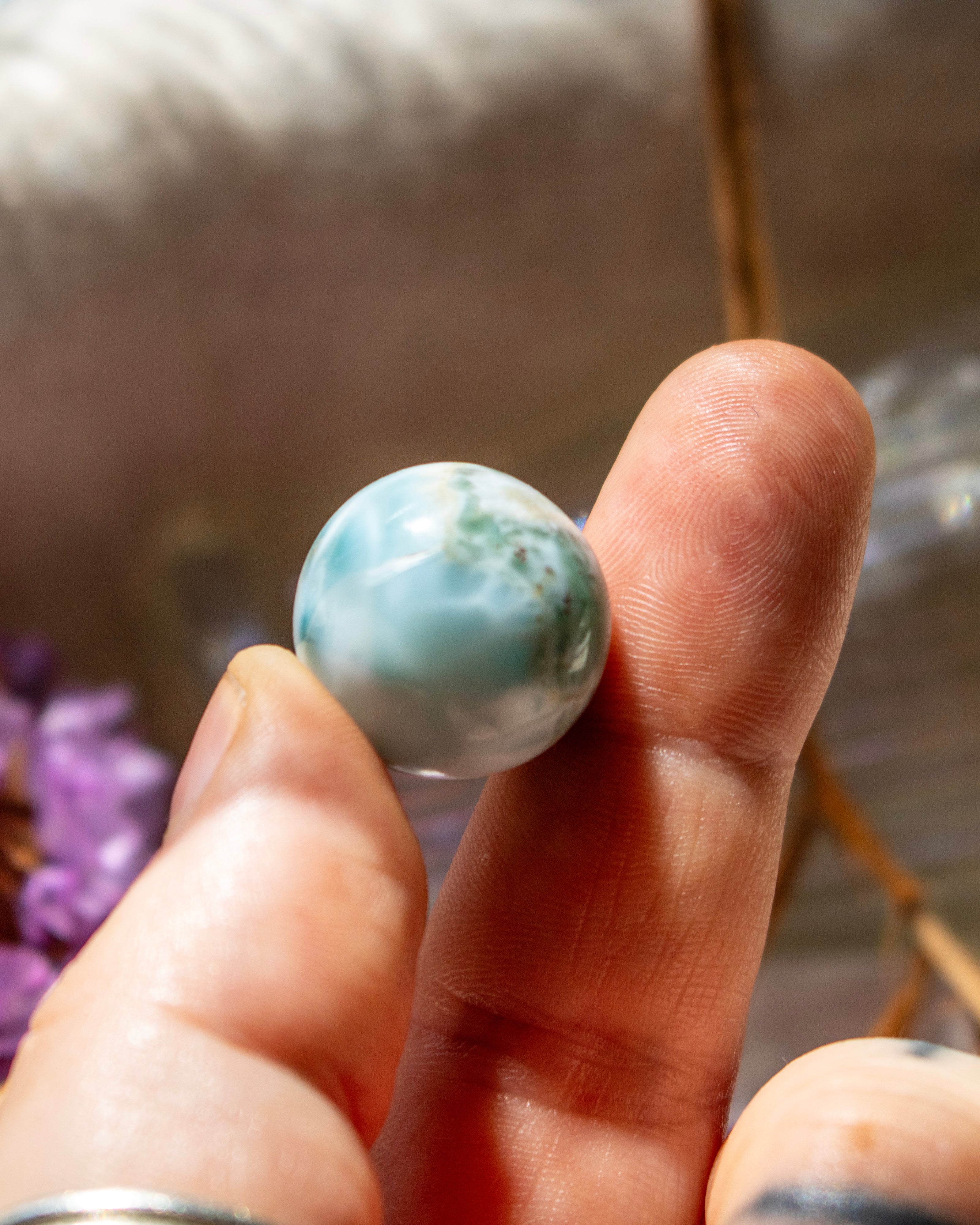 Hand holding a larimar stone against a blurred background
