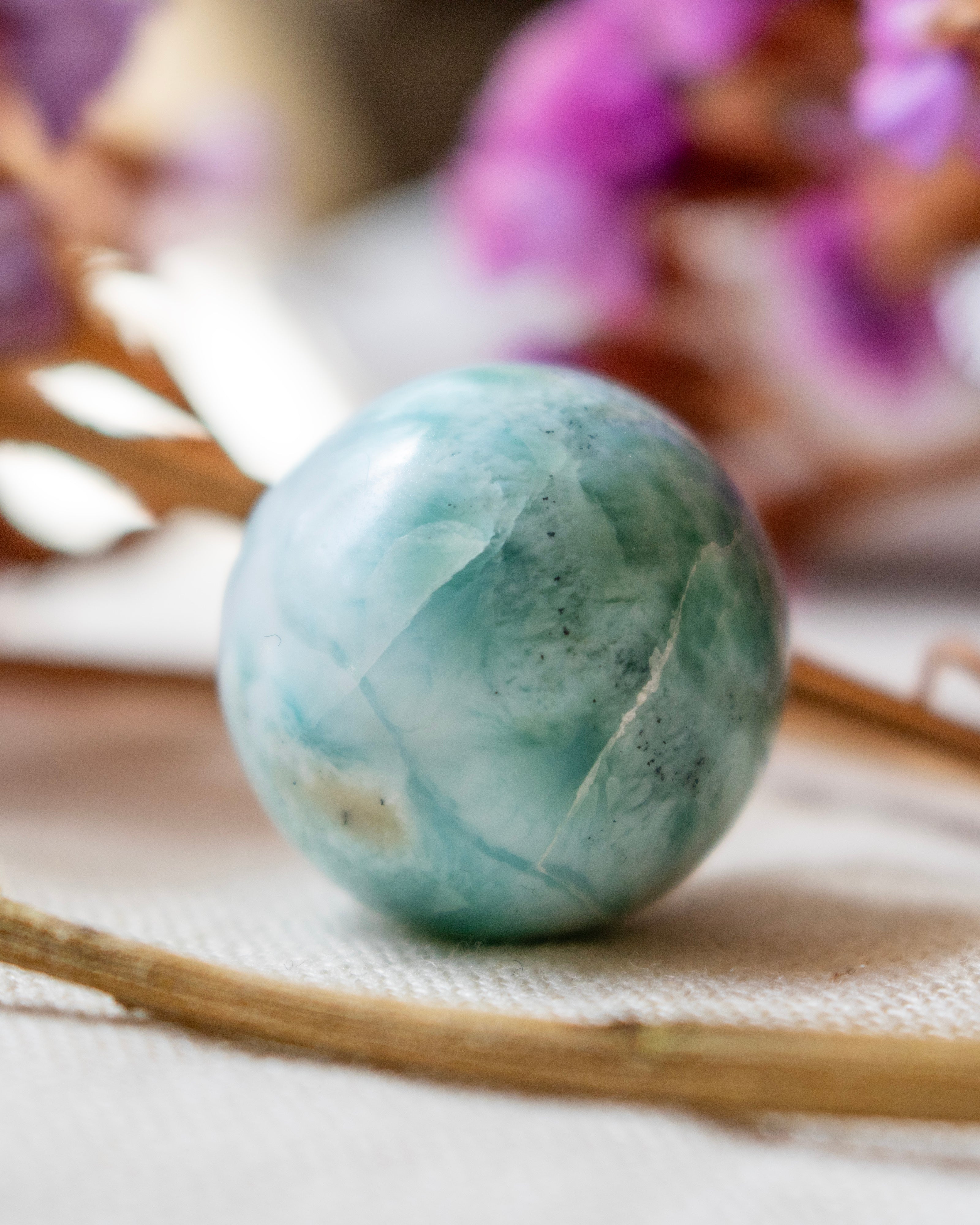 Marbled green and blue sphere on a textured surface with blurred background