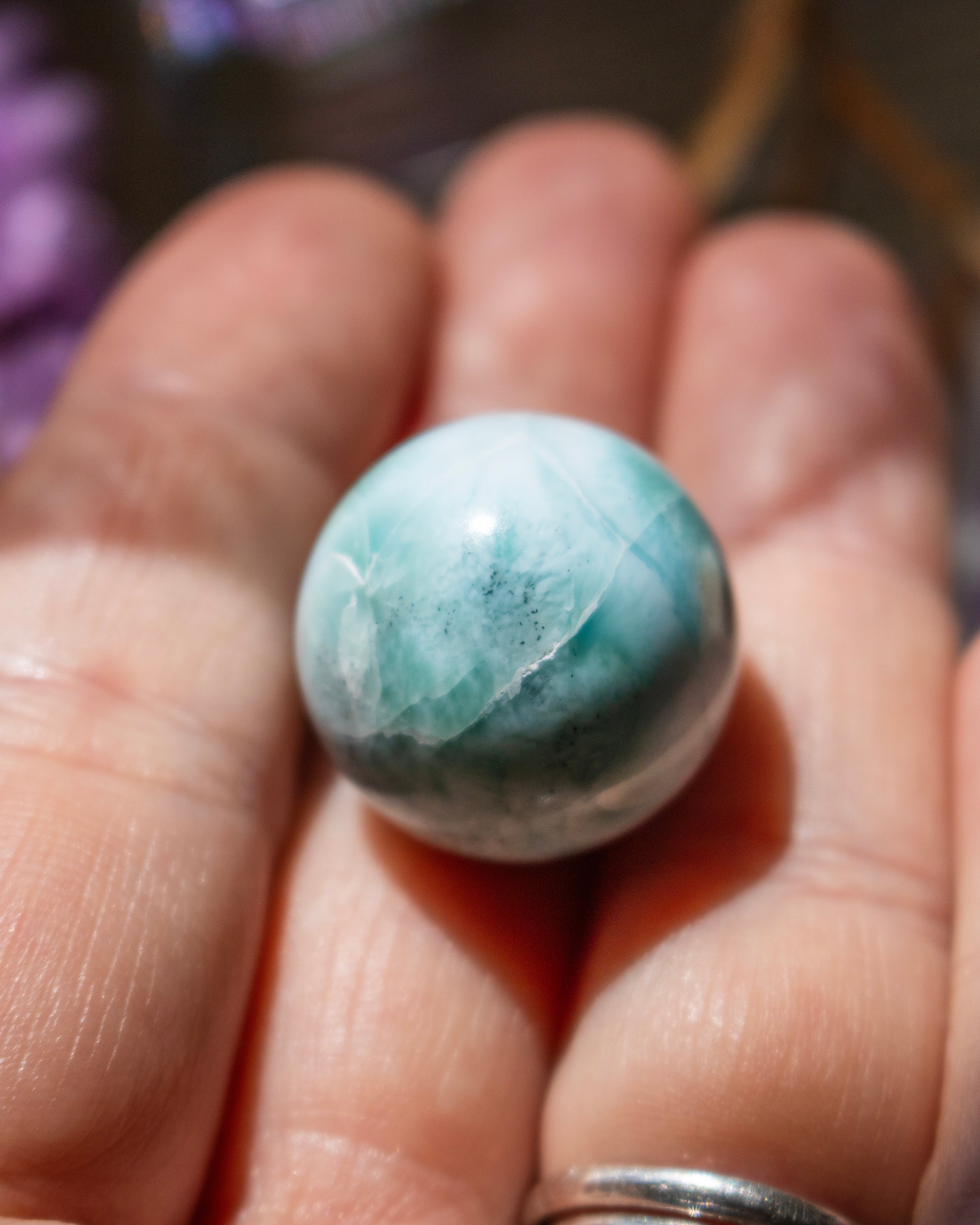 Turquoise stone held between fingers with a blurred background