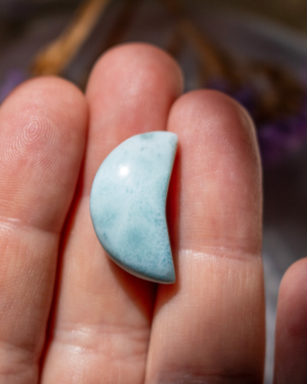 Light blue stone held between fingers against a blurred background